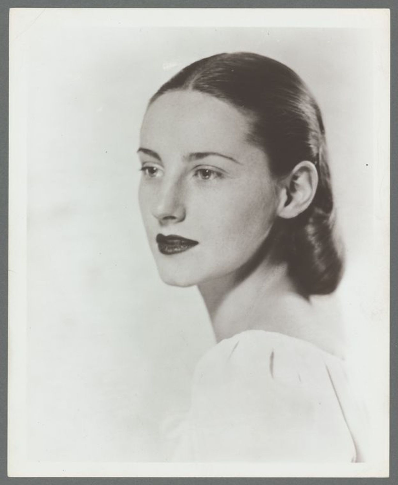 hotographie en noir et blanc de Tanaquil Le Clercq, avec les cheveux foncés coiffés en chignon bas. Elle porte un chemisier ou une robe.