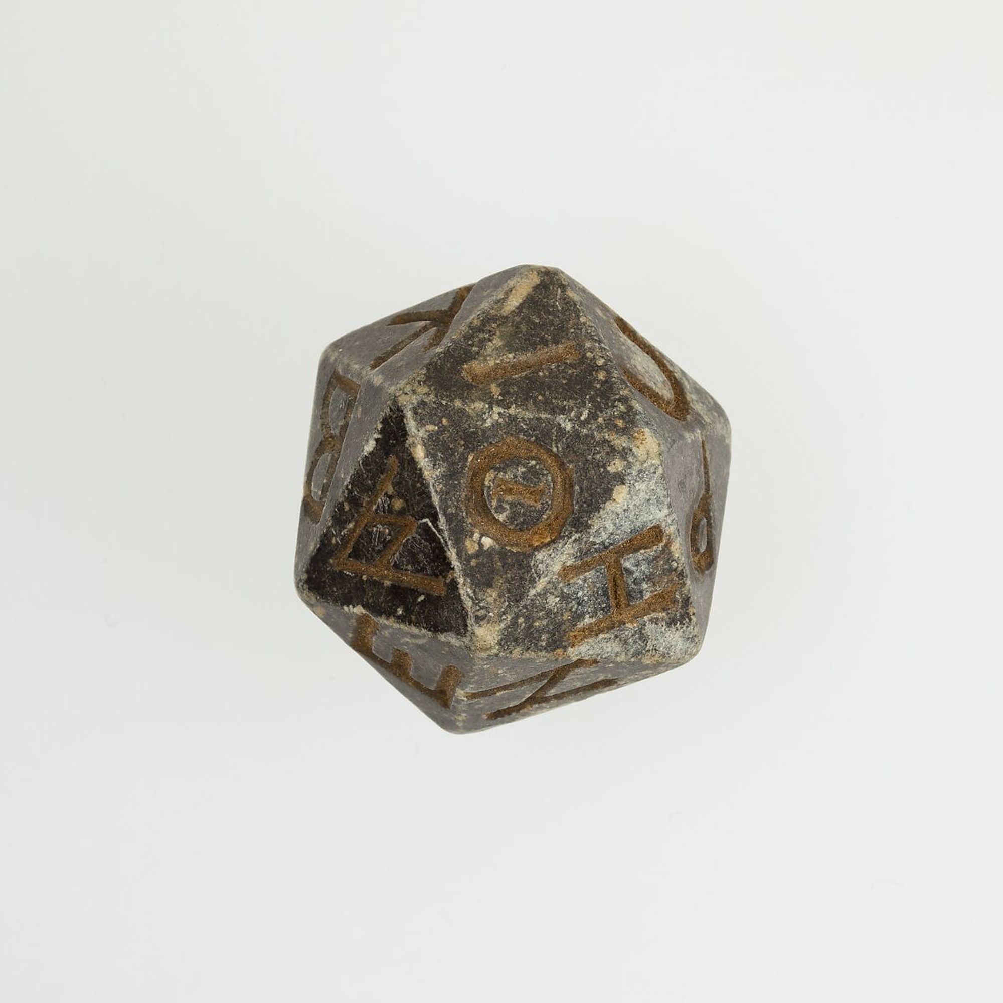 An ancient grey d20 with Greek letters written on it