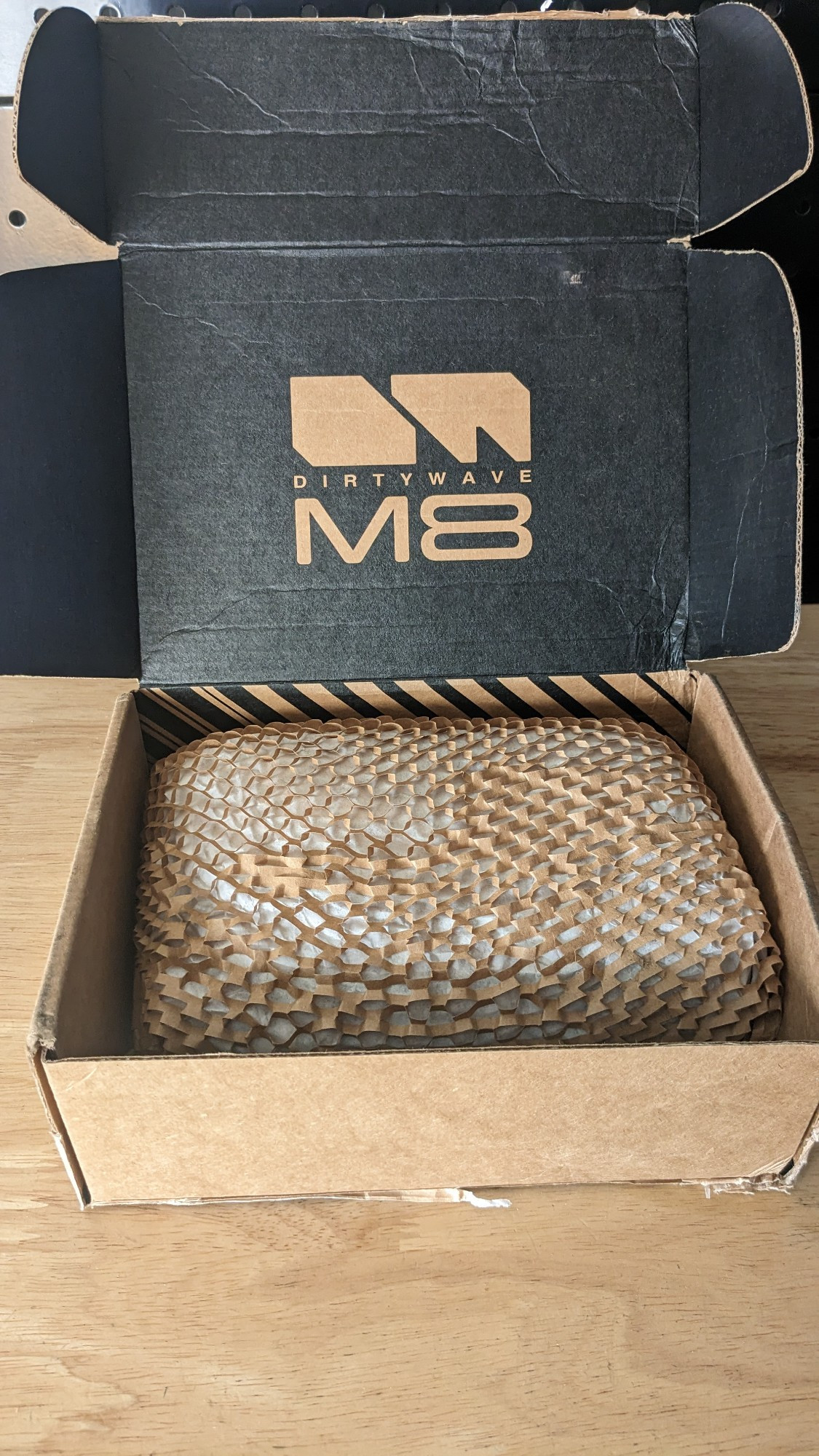 A small cardboard box open with "dirtywave m8" printed inside 