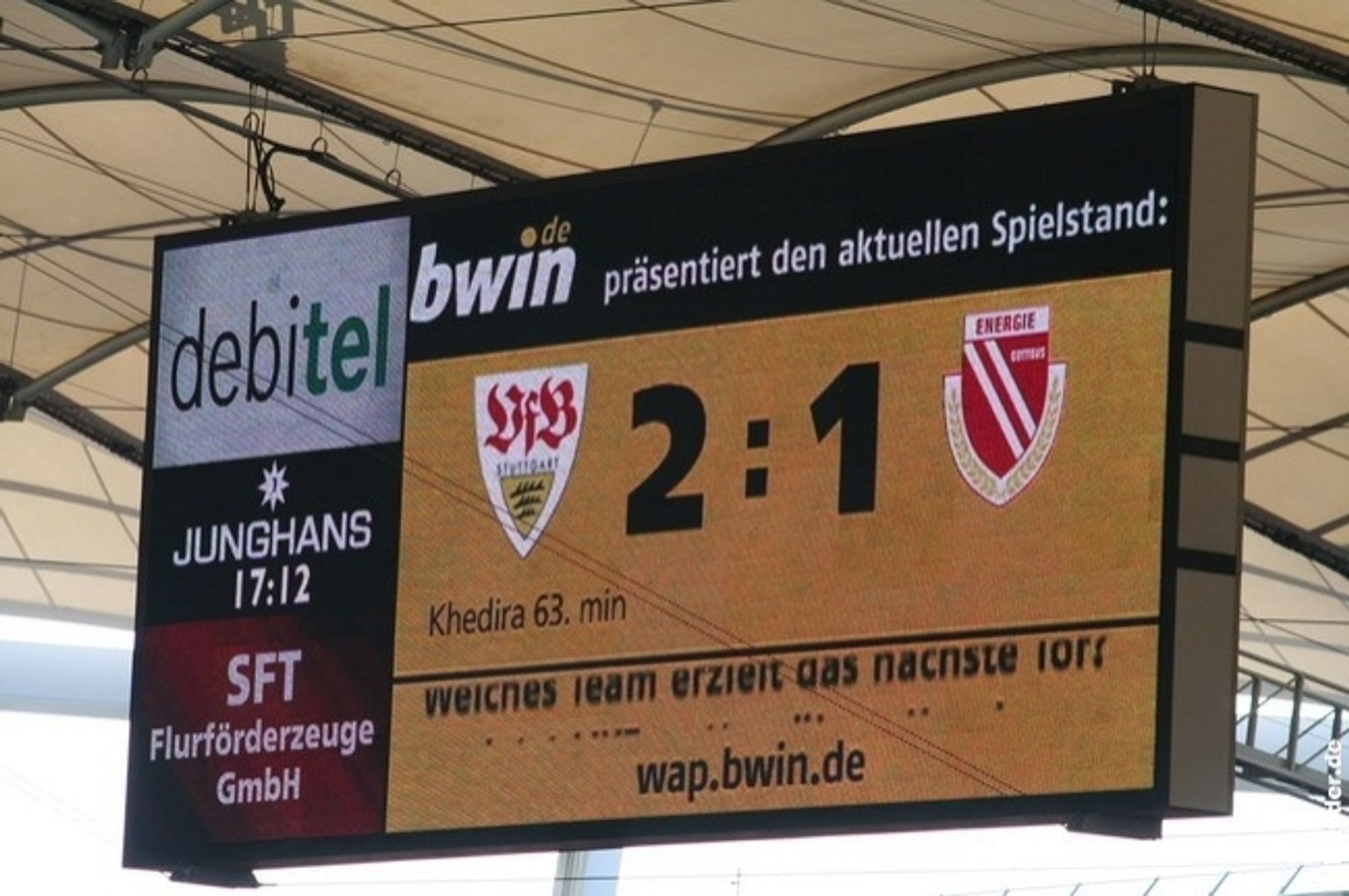 Das Bild zeigt eine elektronische Anzeigetafel die in einem Stadion hängt. Sie zeigt das aktuelle Ergebnis eines Fußballspiels zwischen zwei Mannschaften an. Es steht 2:1 für den VfB Stuttgart gegen Energie Cottbus. OK