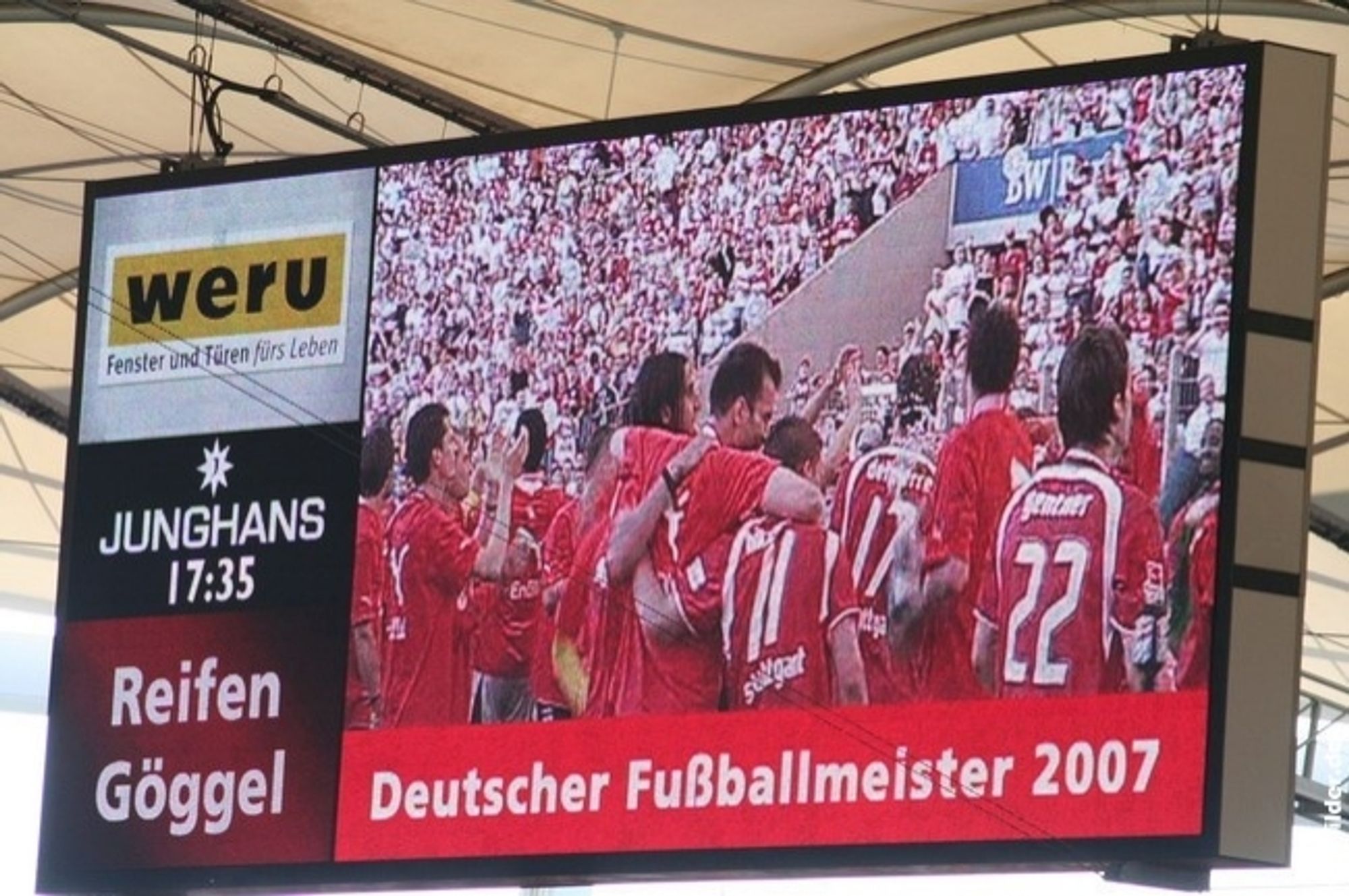 Das Bild zeigt eine elektronische Anzeigetafel die in einem Stadion hängt. Sie zeigt live Bilder aus dem Stadion von der Meisterfeier. Im Bild steht groß "Deutscher Fußballmeister 2007".