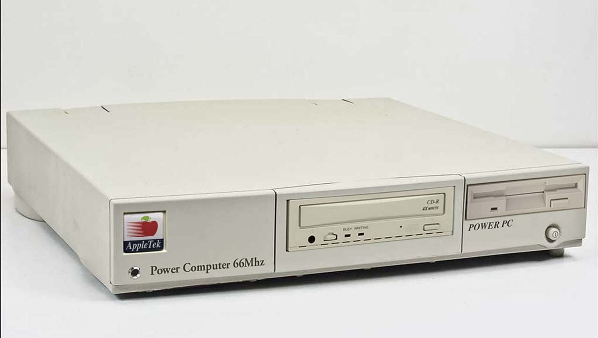 A photo of a generic pizzabox beige pc case with an AppleTek logo in a square in the case, domed with clear plastic resin and slightly off to the side. It's branded "Power Computer 66Mhz" in a fat plain almost-garamond, with a chrome LED bezel sticking out. In the front centre not matching the colour is a slightly offset CD burner, and to the right is a 3.5" floppy bay with some text that doesn't match the other text simply stating "POWER PC". On the front of this computer alone are at least 6 different fonts, three plastic colours and an insult to humanity.