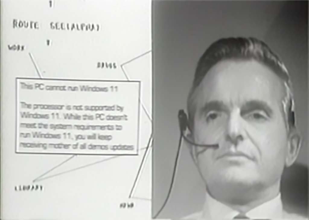 A screenshot of Douglas Engelbart presenting the Mother of All Demos in 1968. A popup in the middle of the screen reads "This PC cannot run Windows 11. The processor is not supported by Windows 11. While this PC doesn't meet the system requirements to run Windows 11, you will keep receiving mother of all demos updates". Engelbart looks unimpressed.