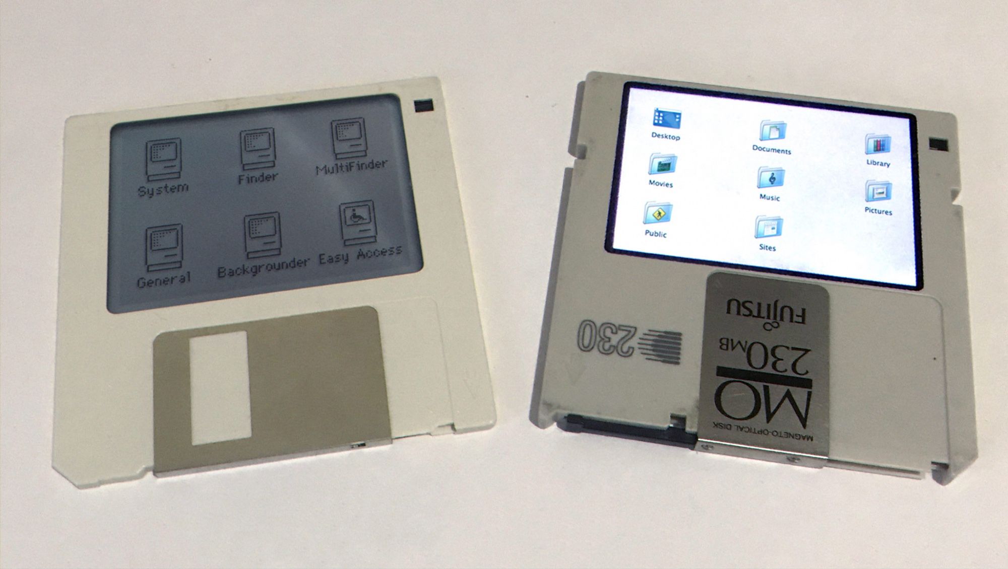 A picture of two disks on a beige background. On the left is a normal 3.5" floppy disk with a greyscale display showing the contents, and on the right is a Fujitsu 3.5" magneto-optical disk also showing the contents but with a colour backlit display.