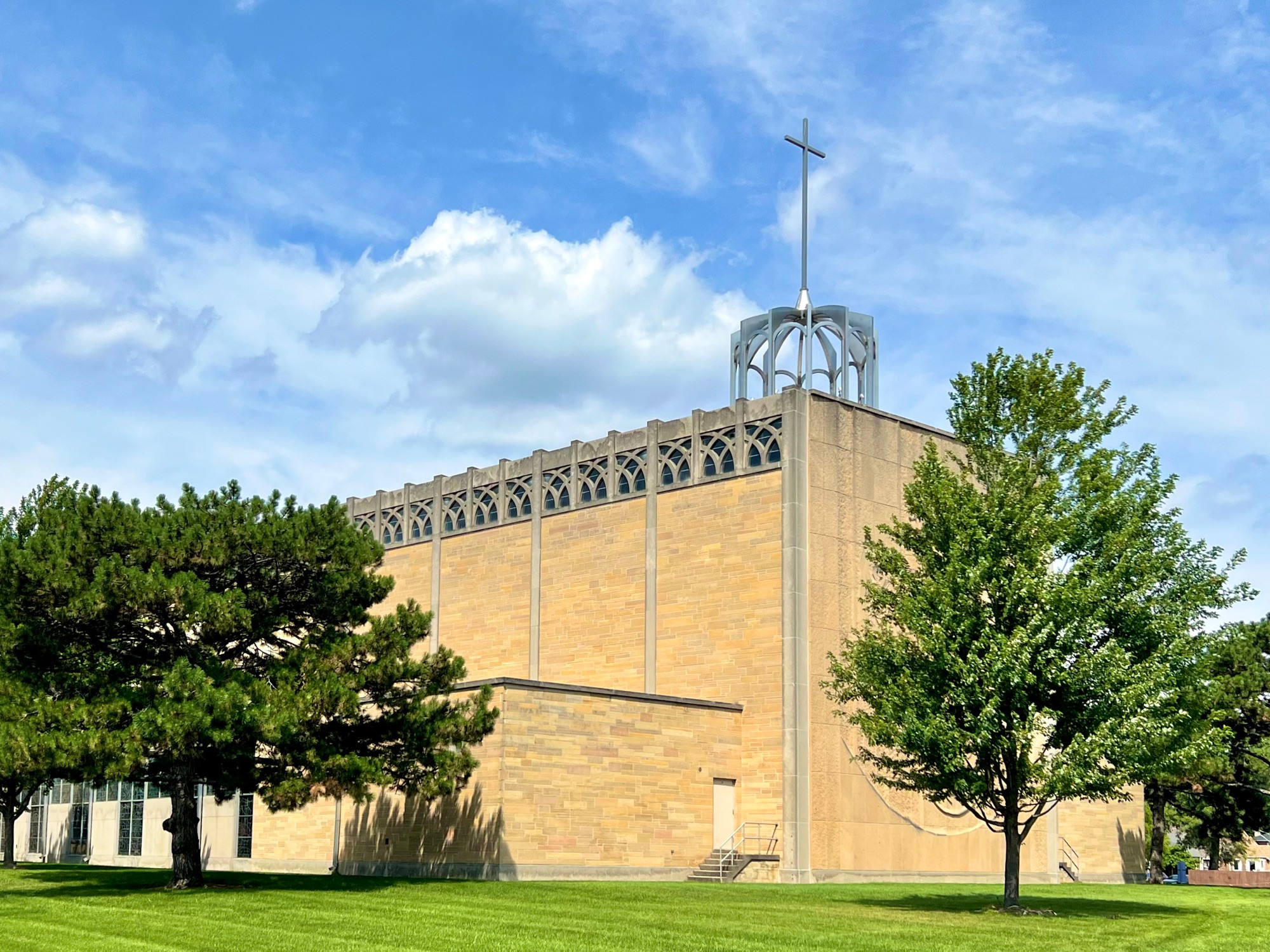 Large rectangular church building with no windows except high clerestory windows with decorative stone tracery.