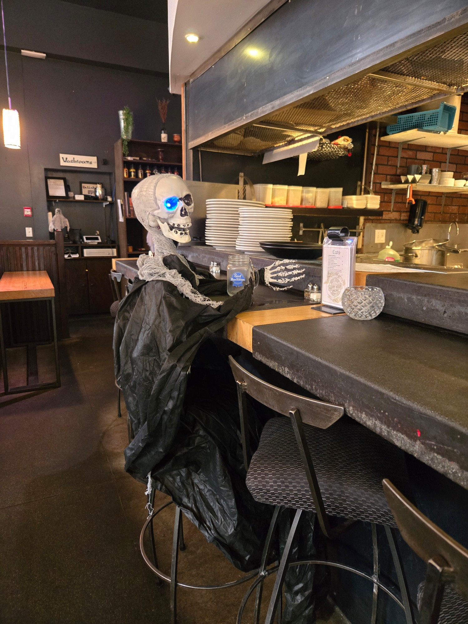 Inside my sons restaurant with a skeleton sitting at the bar holding a pabst blue ribbon beer glass. 