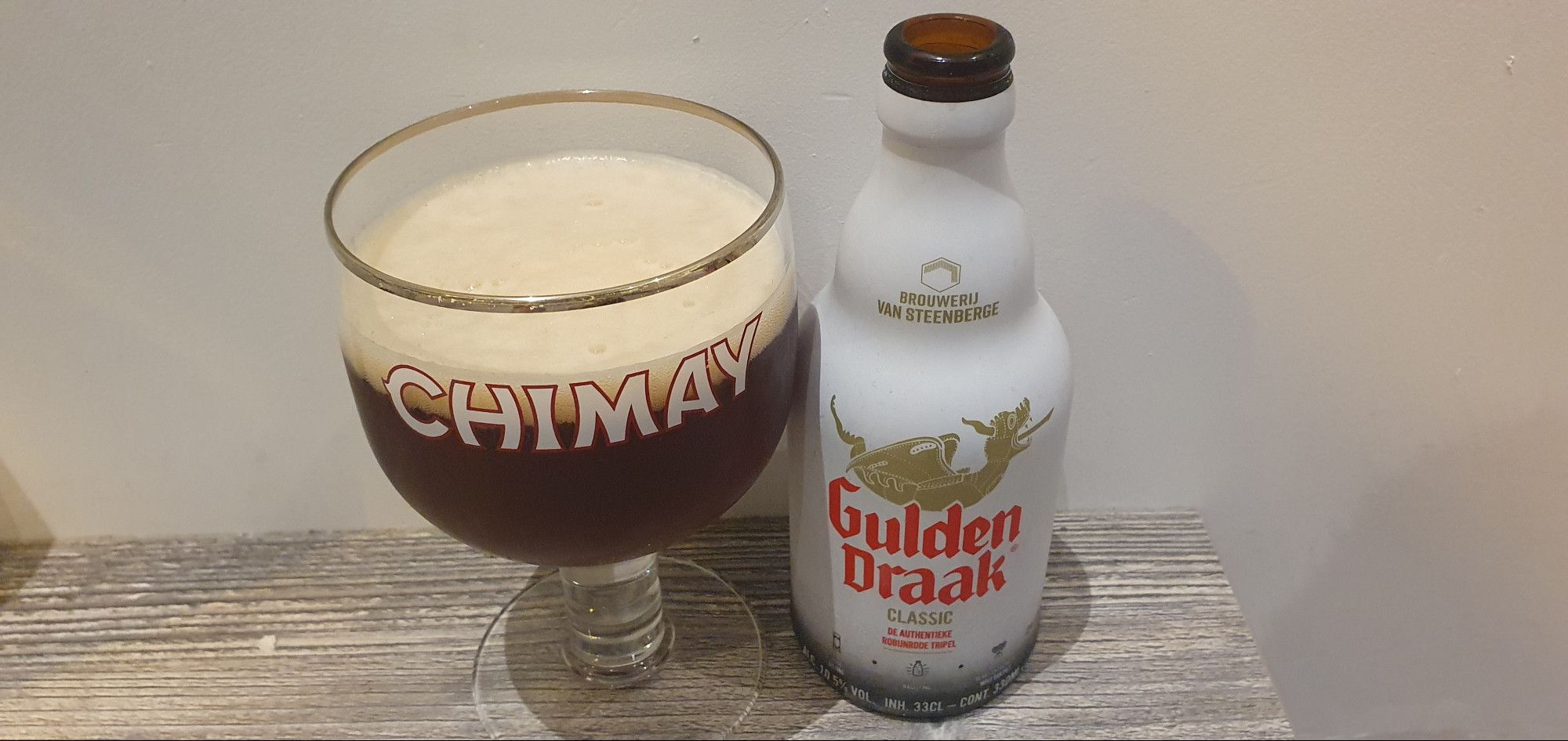 Verre et bouteille de Gulden Draak (bière belge). Le nom de la bière est un hommage au dragon au sommet du Beffroi de Gand, qui symbolise le pouvoir et l'indépendance. Ce dragon est représenté en doré sur l'étiquette de la bouteille