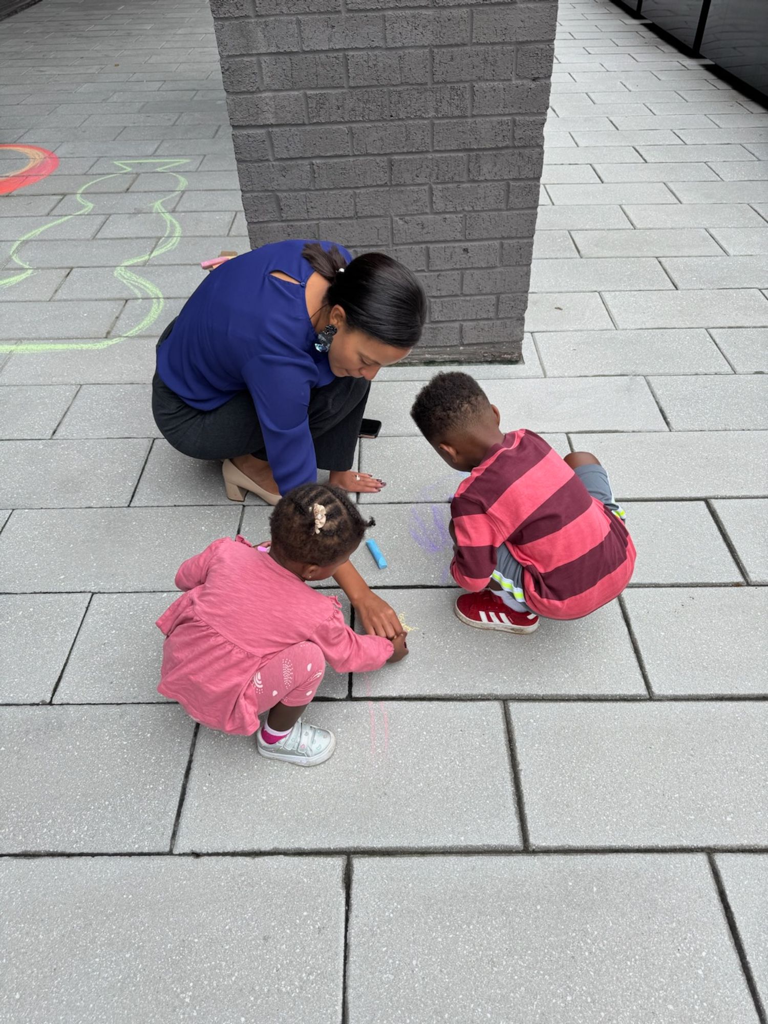 Alyia and her 2 small children draw with sidewalk chalk in North Old Town.