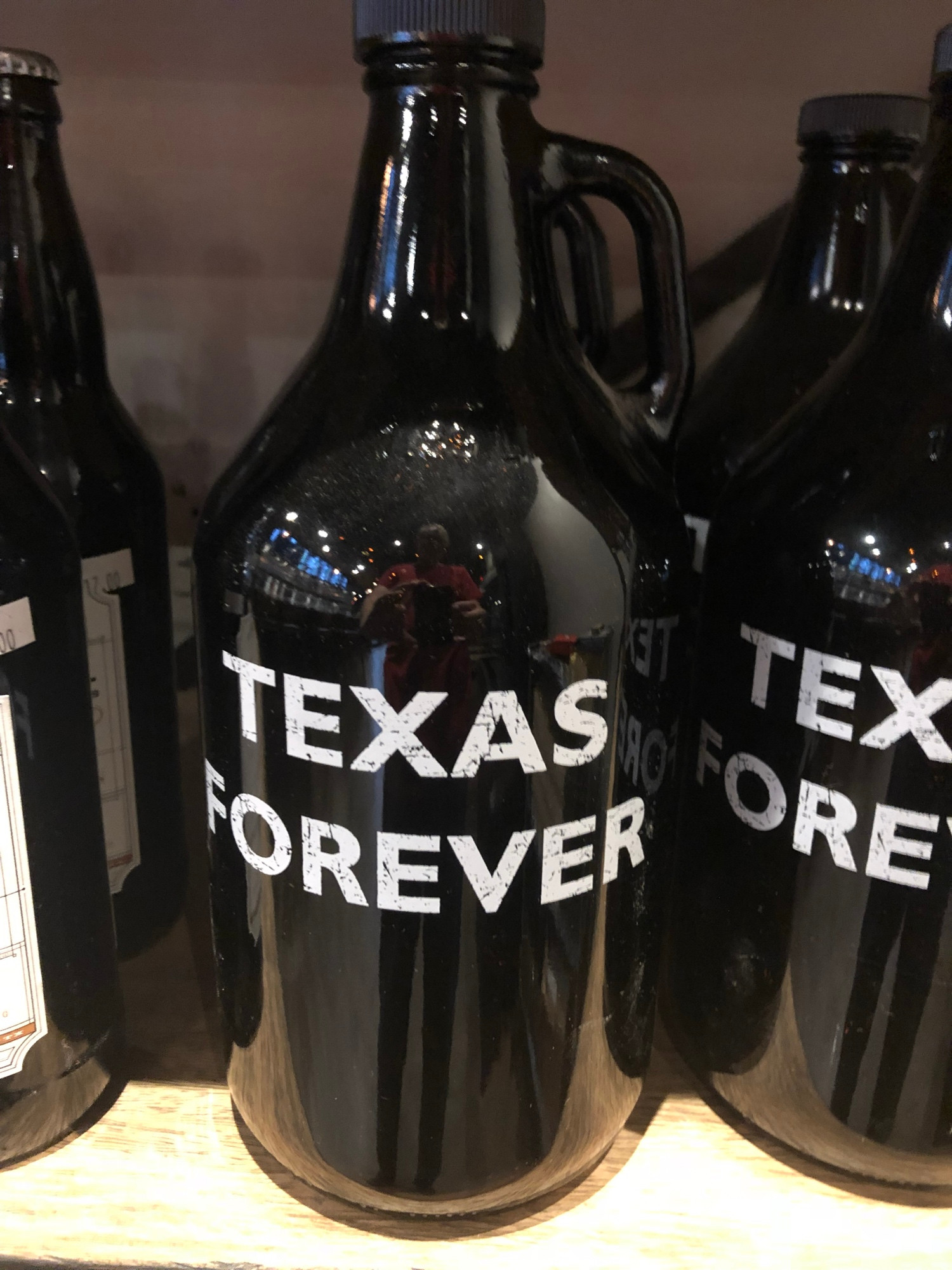A brown growler bottle with large white block letters says “Texas Forever.” Seen at a pub near Dallas.