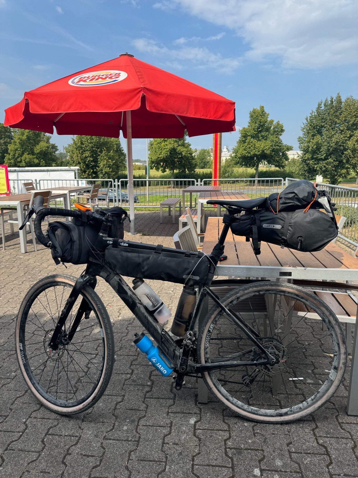 Fahrrad mit Packtaschen vor einem Sonnenschirm.