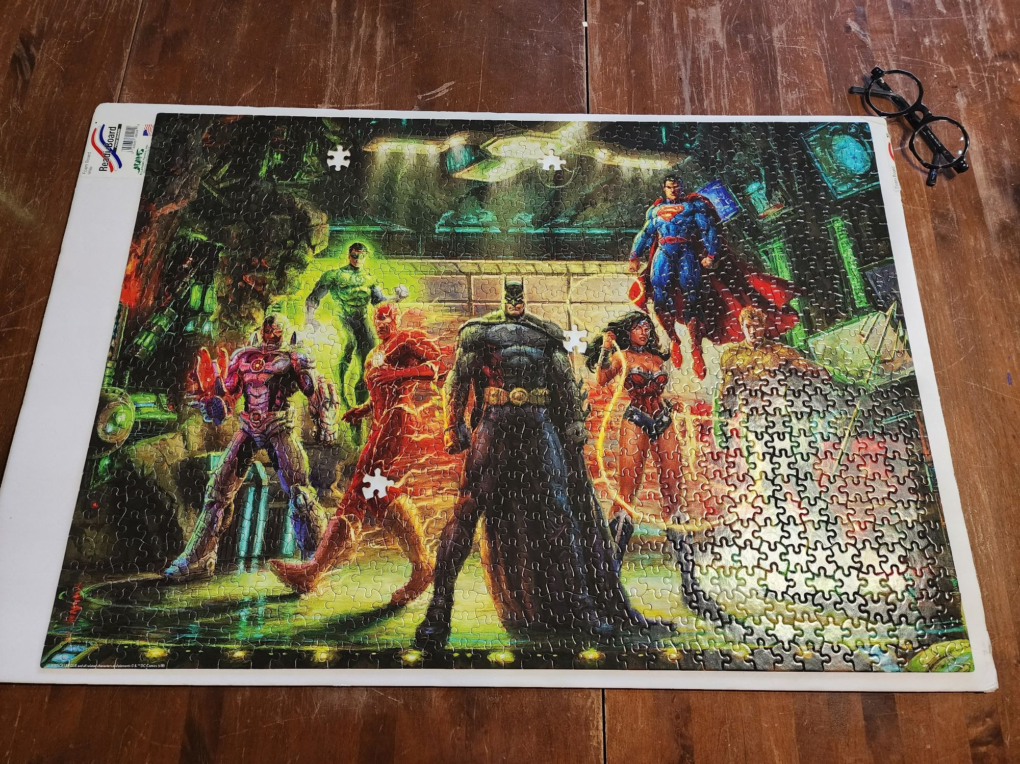 A mostly completed 1000 piece puzzle depicting the Justice League of America missing four pieces.