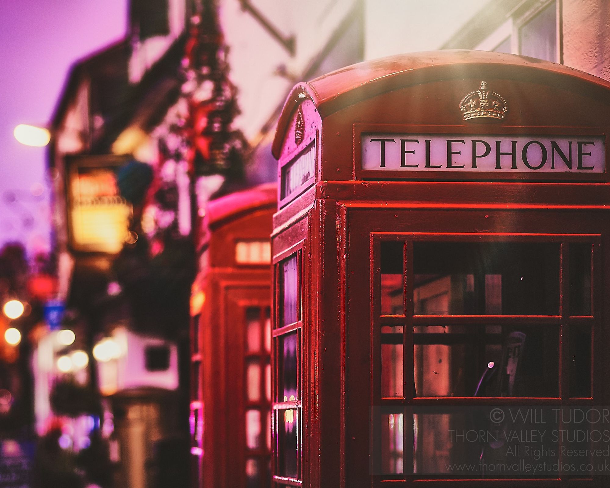 Red English Phone box on a dusklit street in Warwickshire, United Kingdom