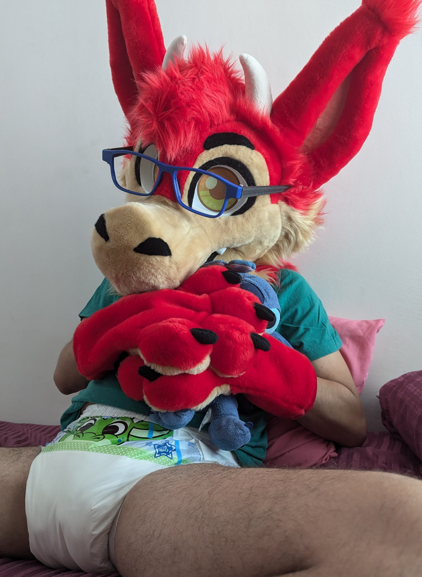 Dragon Fursuiter with diapers hugging a stick plush