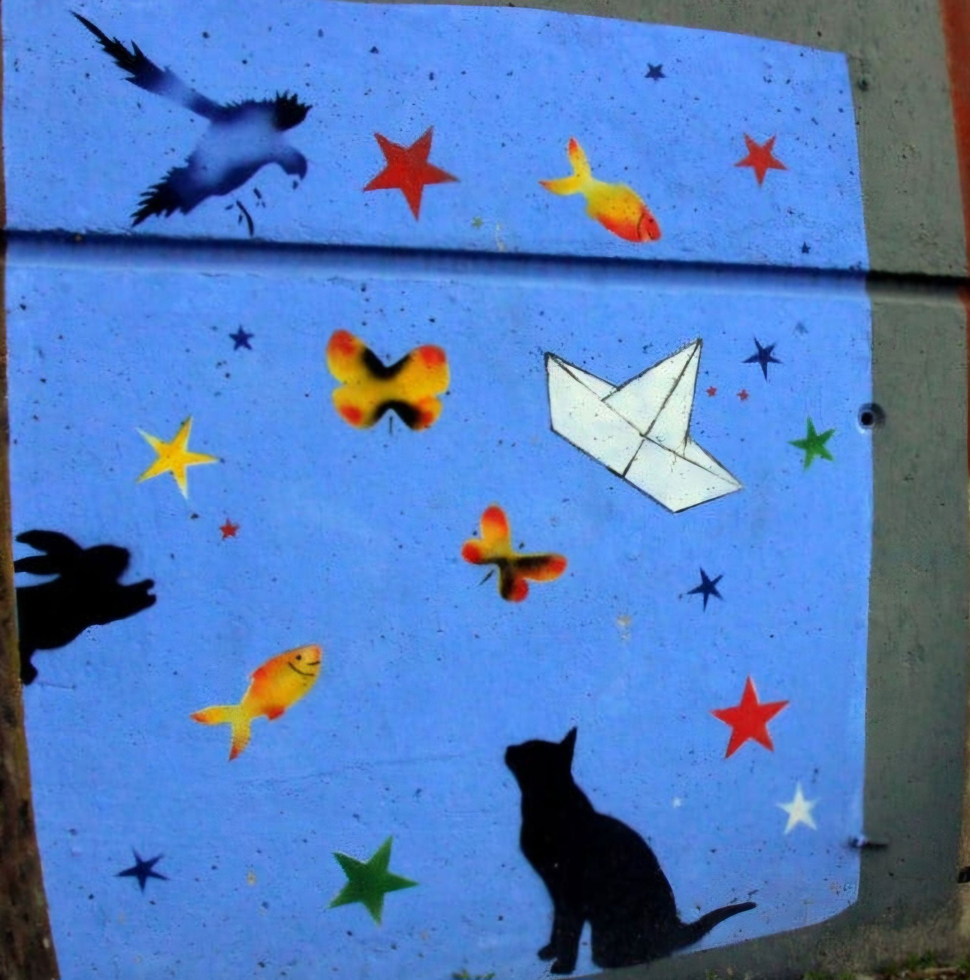 Mural sur fond bleu à Montreuil
Un chat noir lève les yeux au ciel ou il s'y trouve des poissons rouge et  doré, un bateau en papier blanc, des étoiles bleues, vertes, rouges, blanches, jaunes, un lapin  bondissant en silhouette tout à gauche.