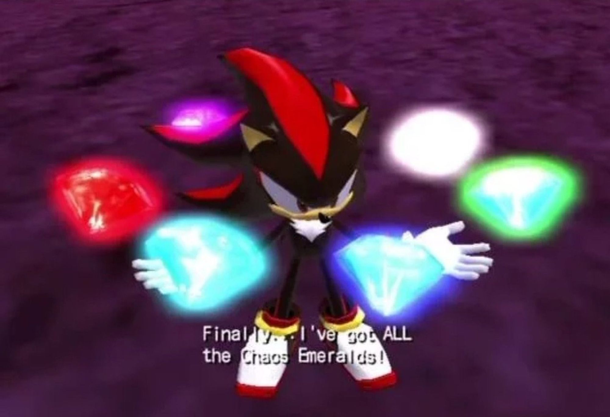 Screenshot from a cutscene from Shadow the Hedgehog depicting the Chaos Emeralds floating around Shadow. The subtitles read "Finally... I've got ALL the Chaos Emeralds!".