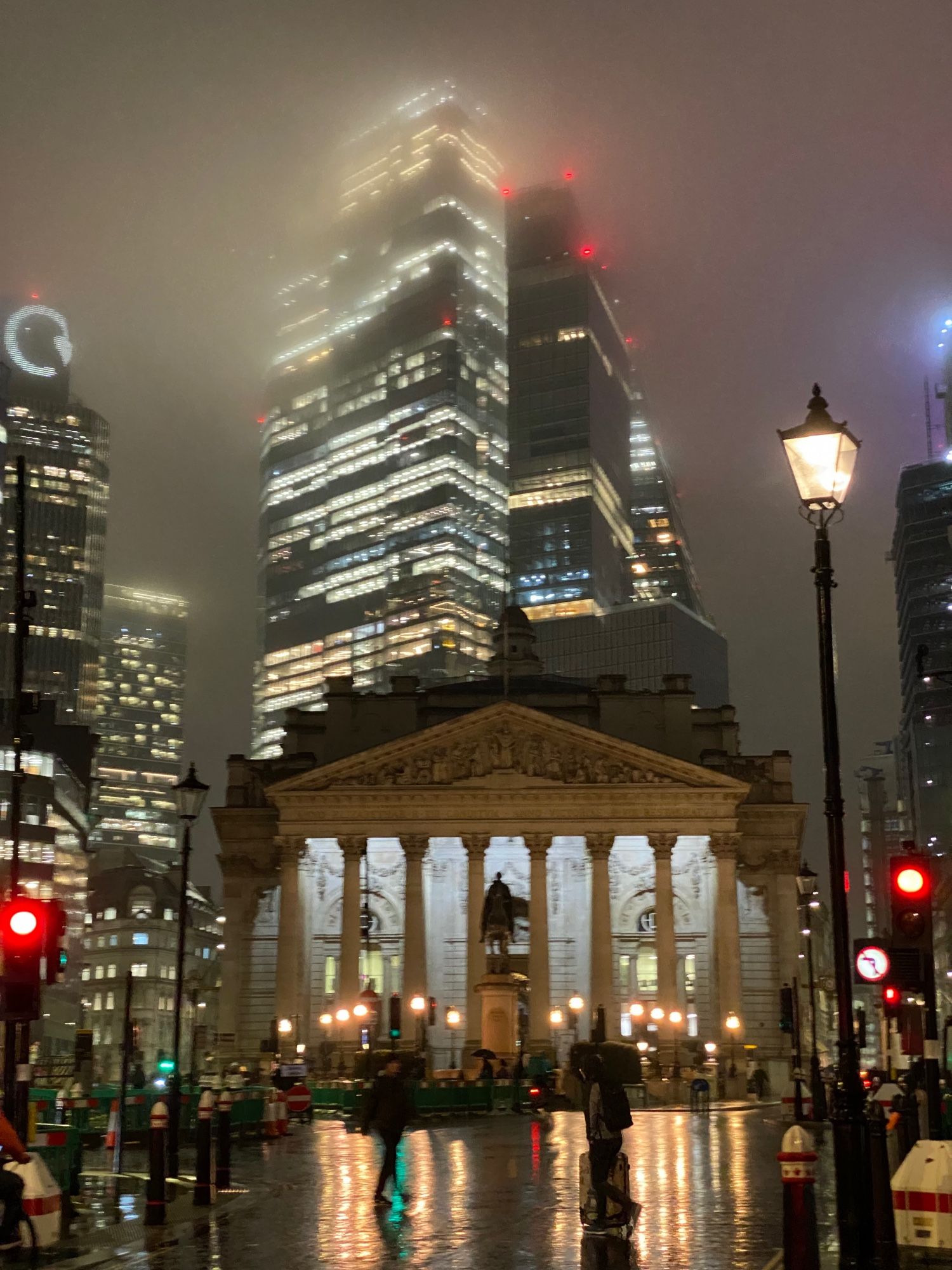 The Bank of England with an illuminated skyscraper behind it, disappearing into mist.