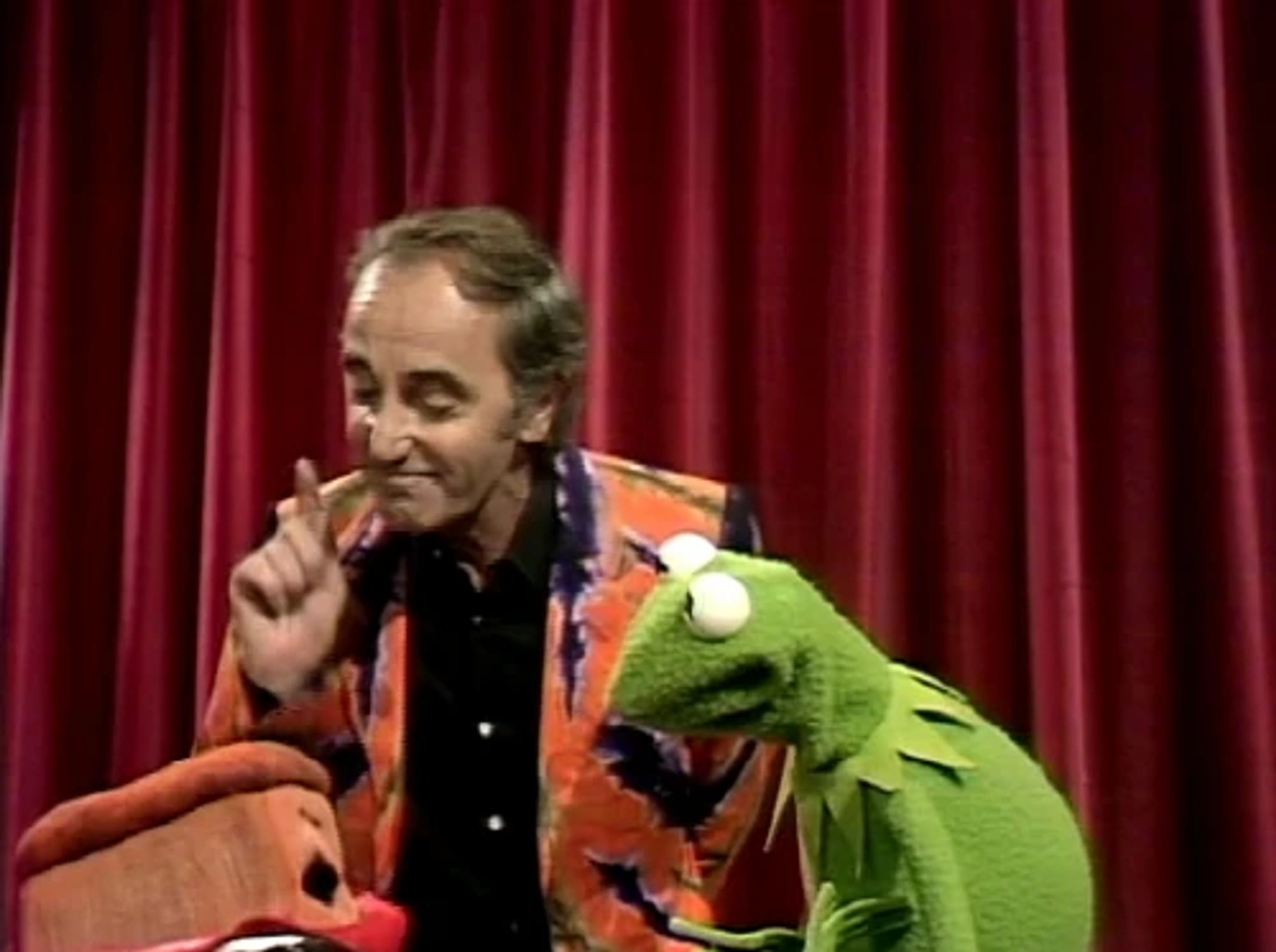 Charles Aznavour at the end of his episode of the Muppet Show, he is with Kermit the Frog and a loaf of bread who is French. Aznavour and the bread have become fast friends