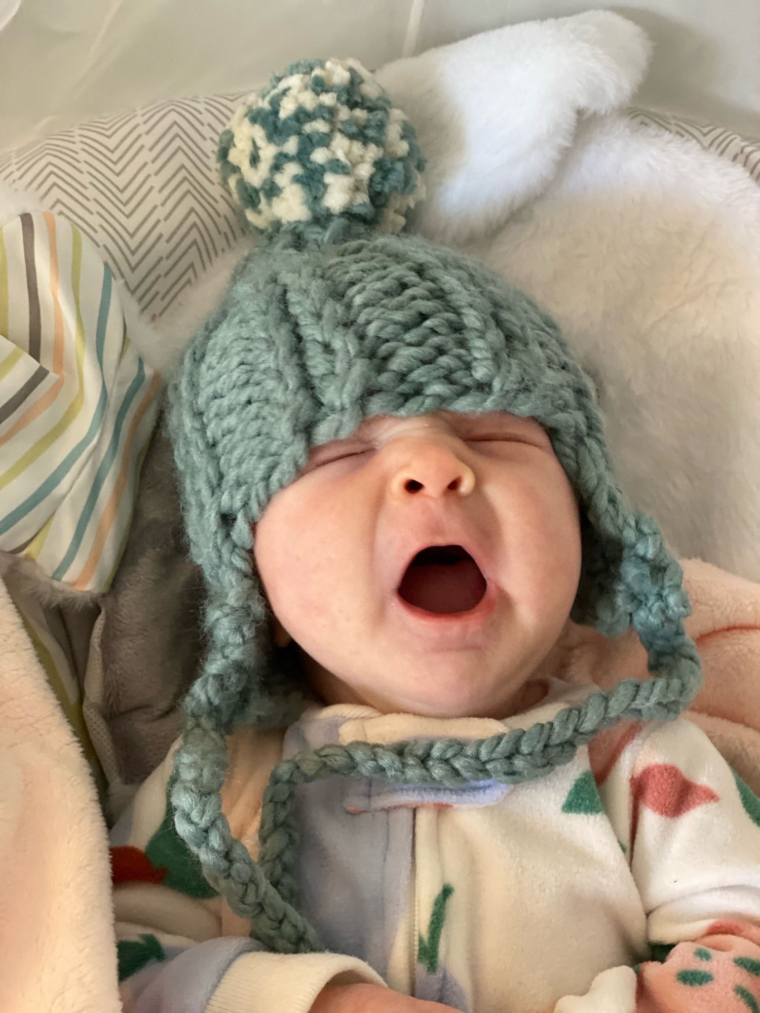 yawning infant wearing knitted hat