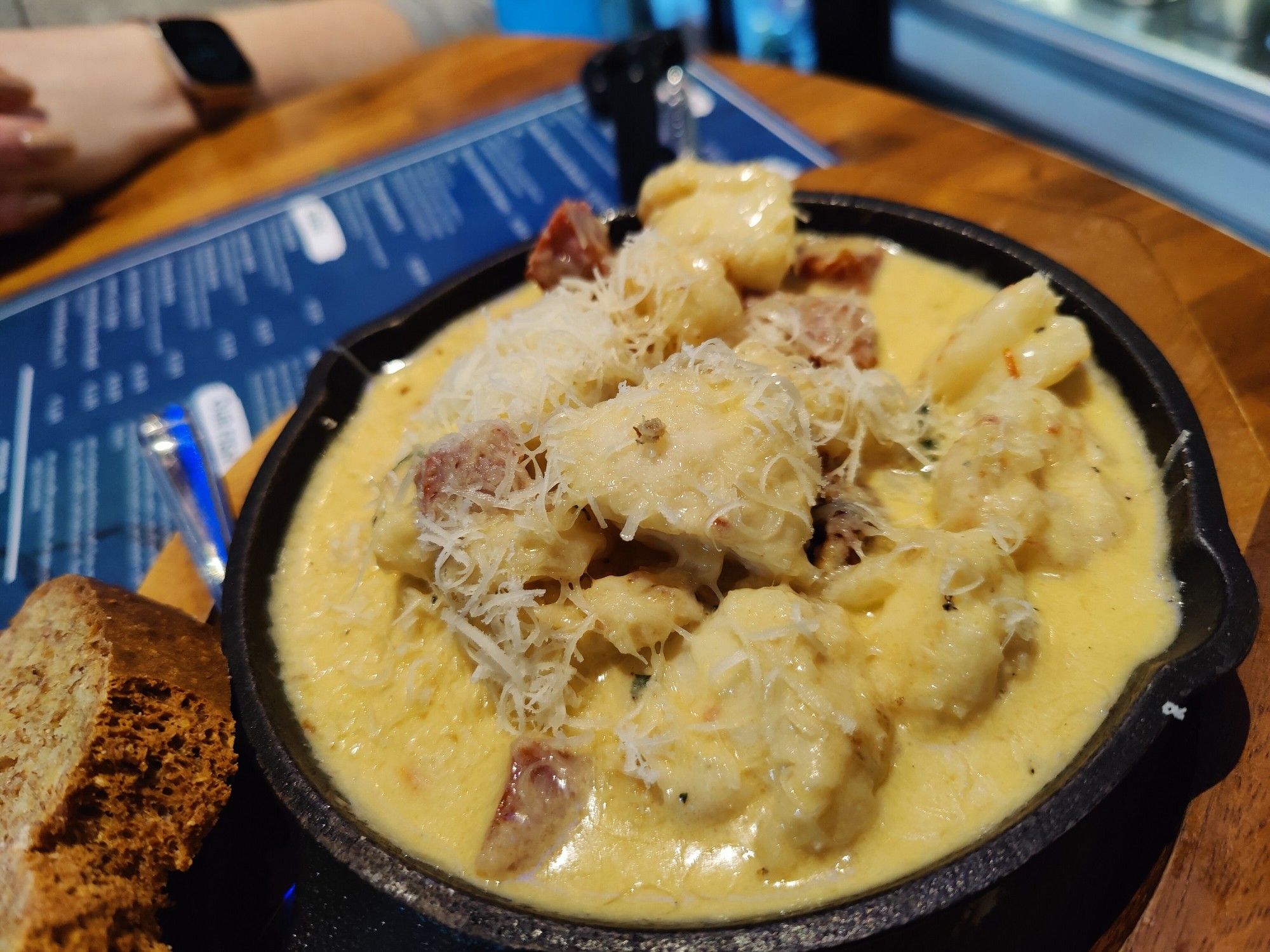 A cast iron pan with a creamy sauce, chunks of monkfish and prawns piled up