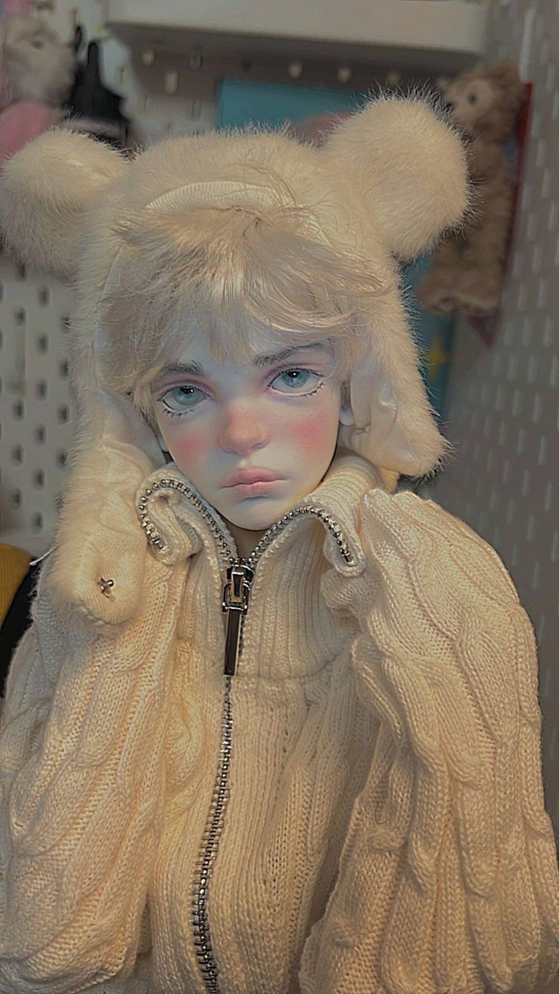 Doll in white sweater and white bear hair hat.