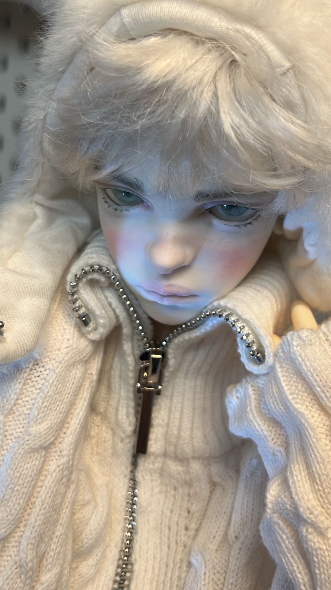 Doll in white bear hat and sweater.