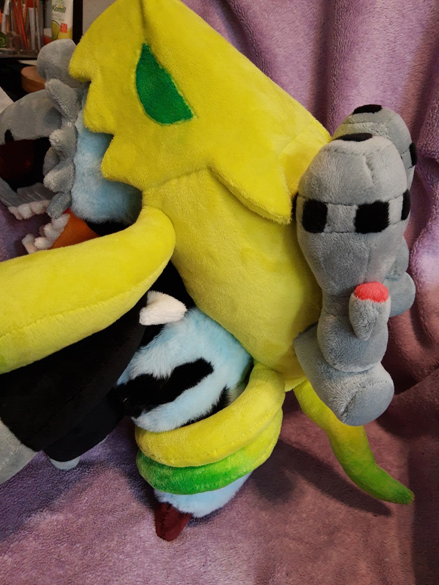 A plushie of the digimon Millenniummon. It's shown from the side to reveal more of the yellow "ghost" riding on its back.