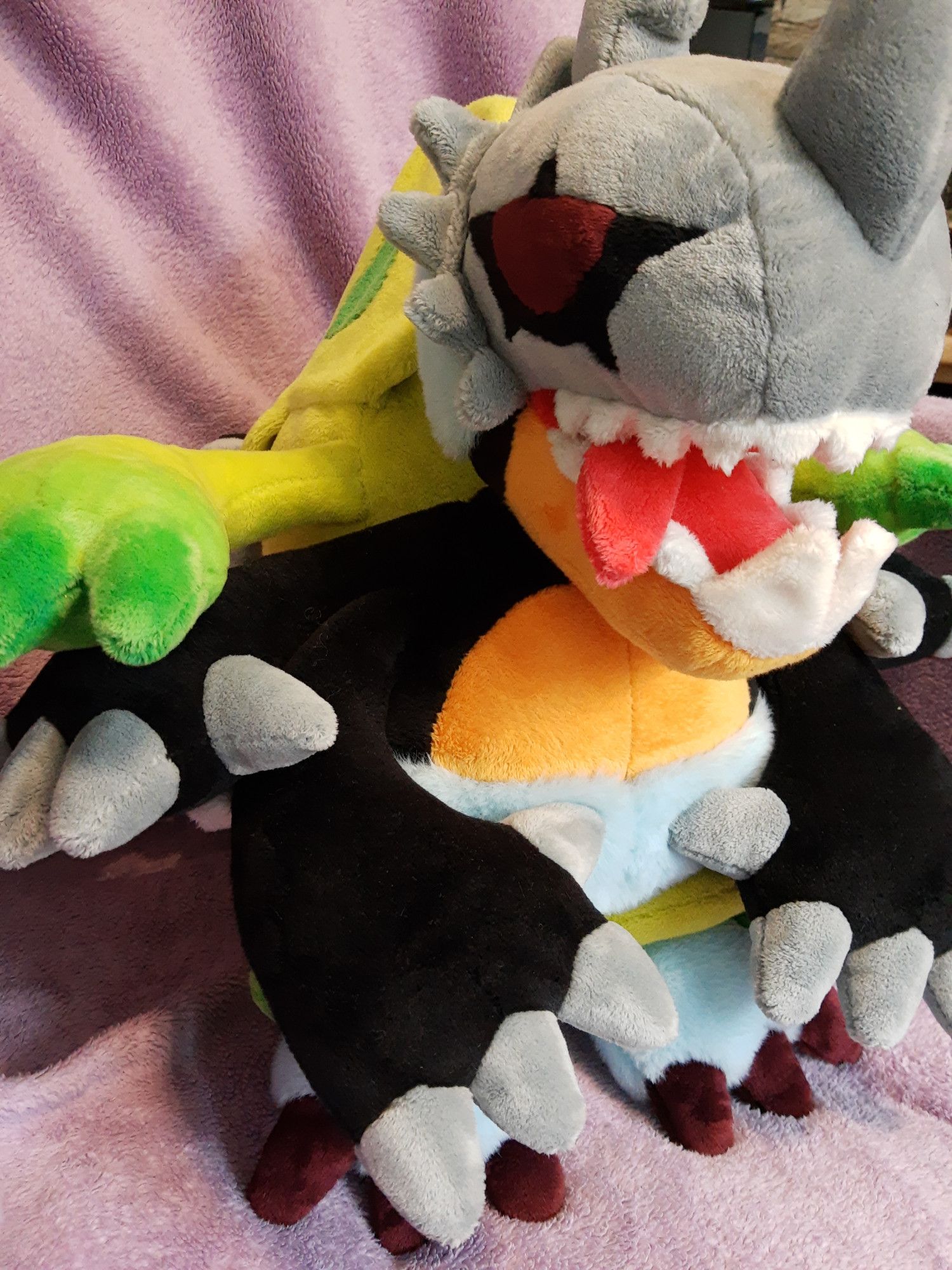 A plushie of the digimon Millenniummon. It's shown from the front and its tongue is poking out of its jaw.