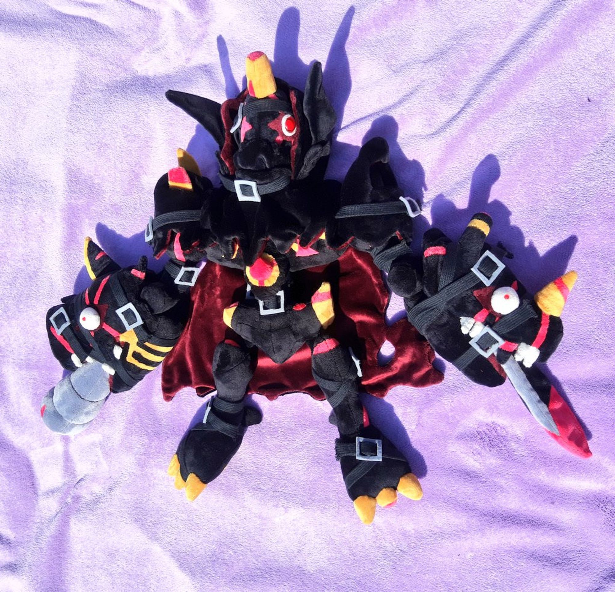 A plushie with a complicated design. It's the digimon Omegamon Zwart Defeat.