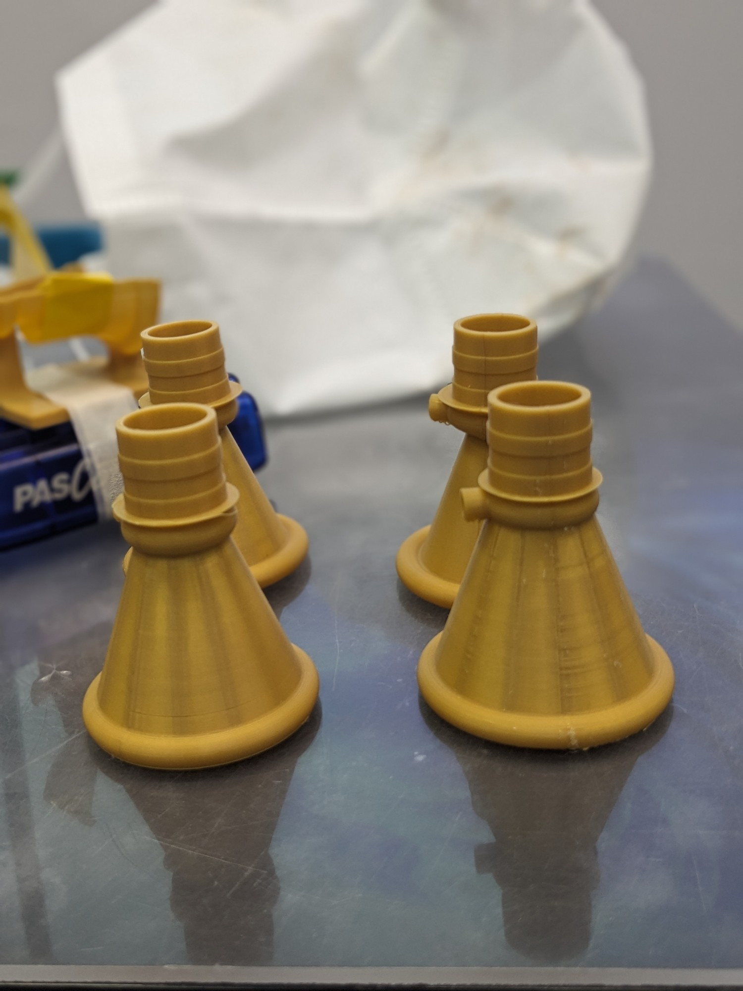 Four 3D printed rocket nozzles, gold coloured