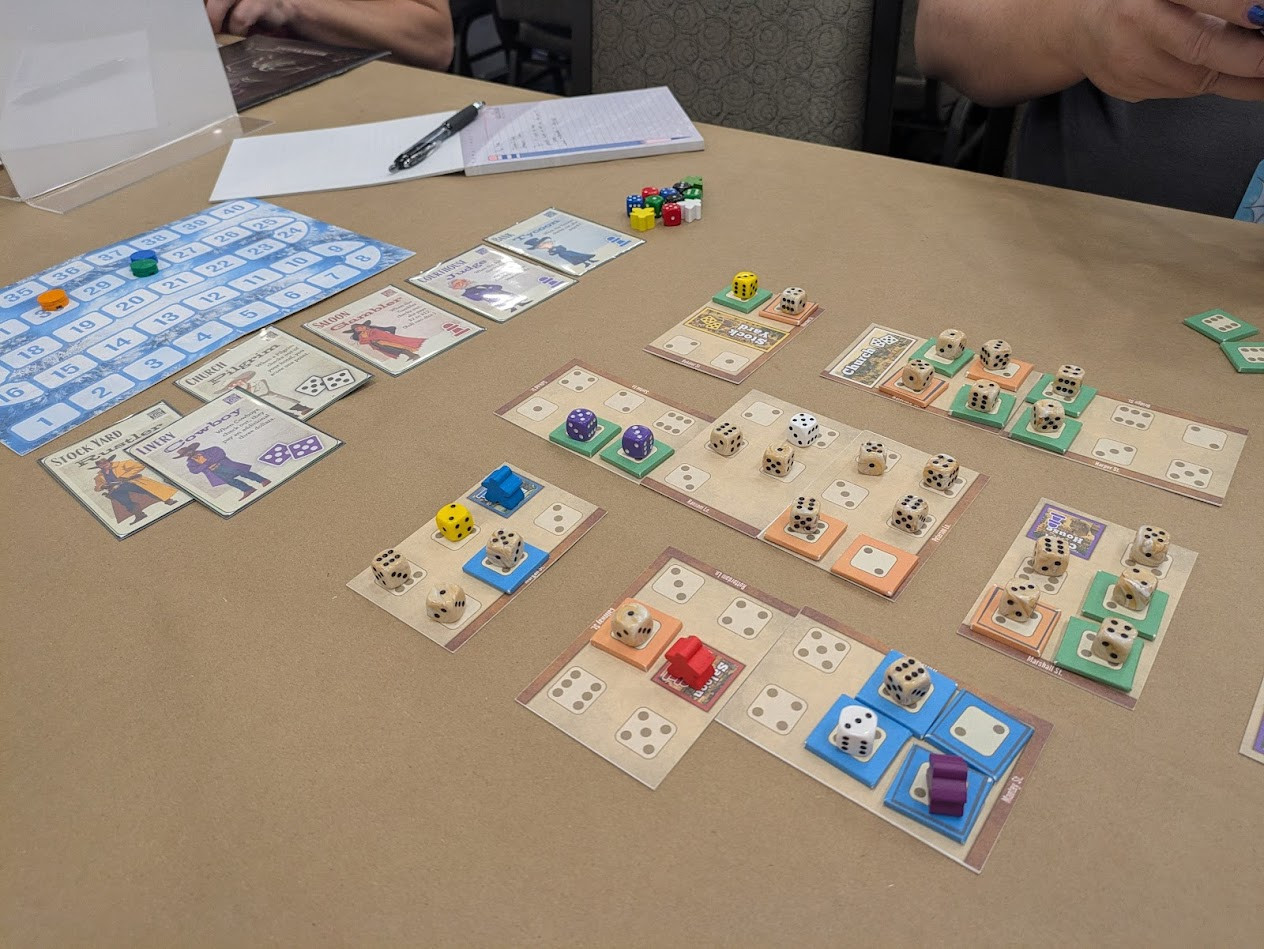 A table showing a scoring track, a few cards with miner charactors on it. Also a layout of cards with dice icons and many small dice occupying those dice icons.