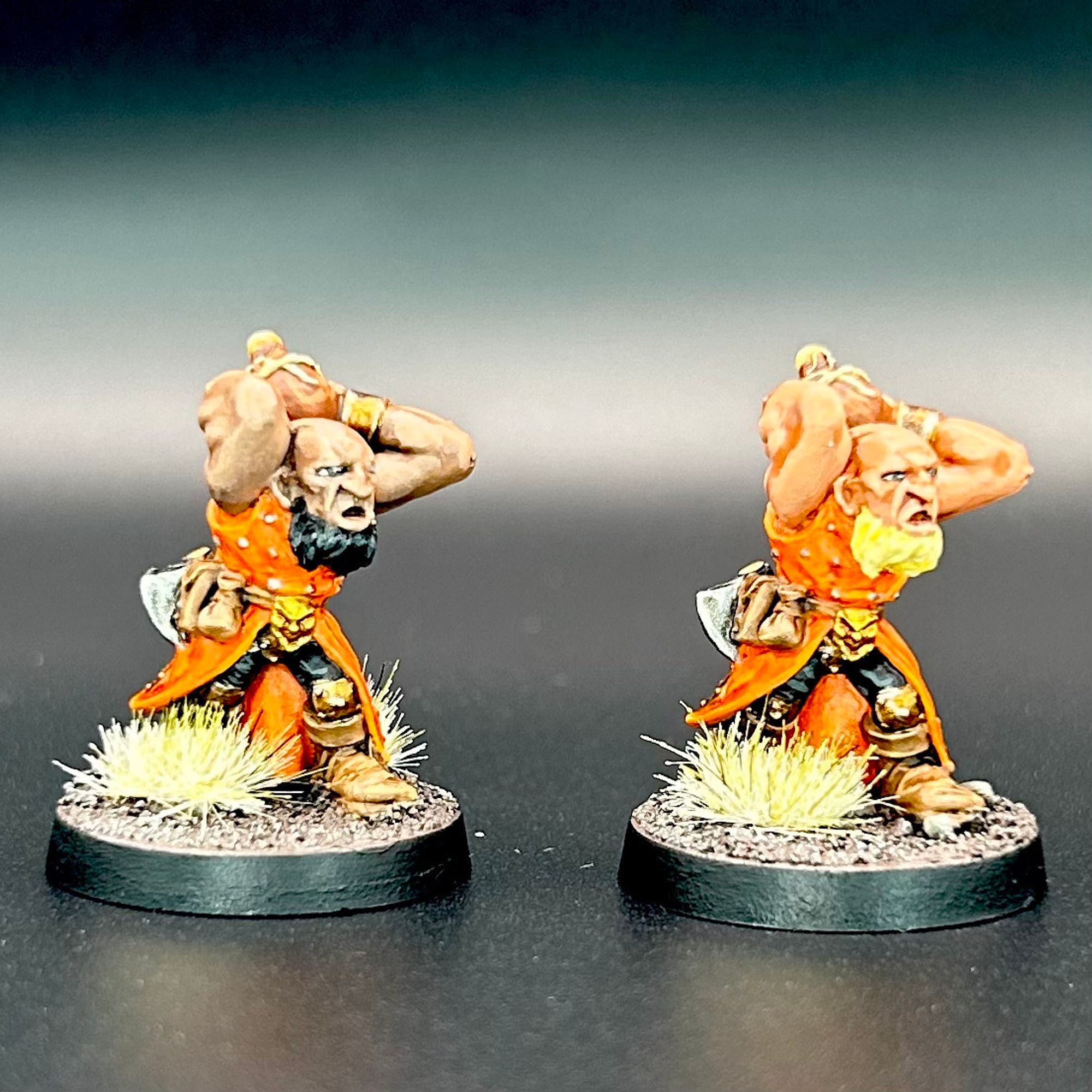 The fronts of two dwarf scorcher miniatures from the Mordengard faction. They're bearded dwarfs with orange cloaks, throwing closed pots overhead.