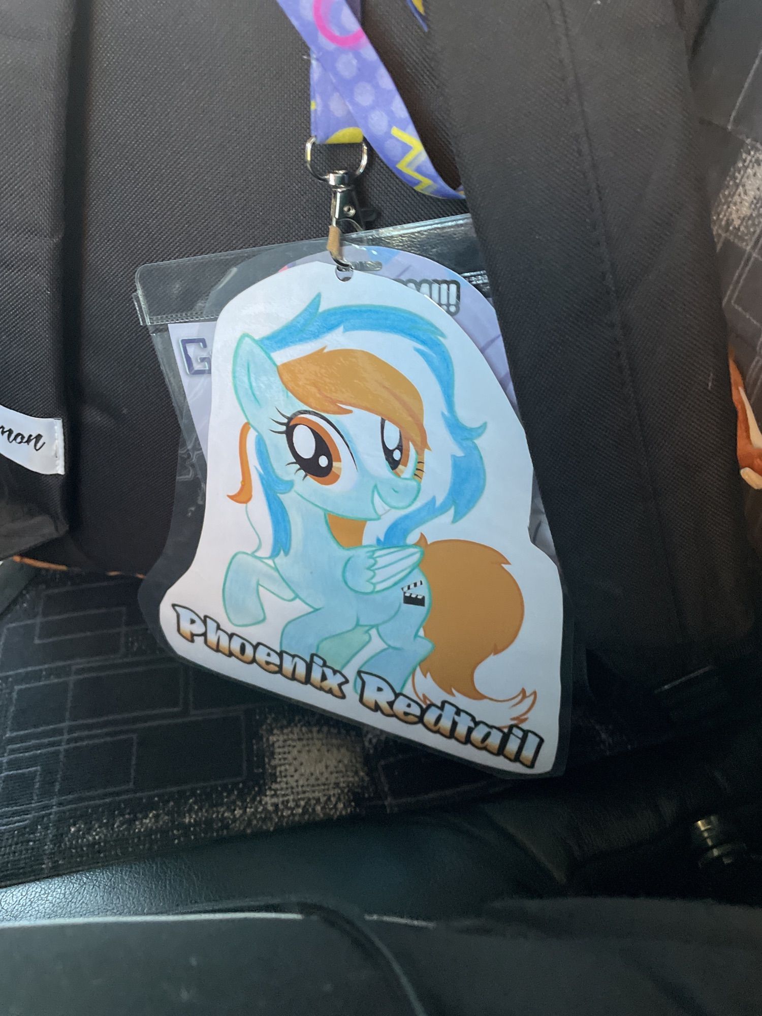 My con badge! Just a pic of my pony with the words “Phoenix Redtail” on it as I excitedly approach Dublin for Furry Not New Years/FNNY 2024.