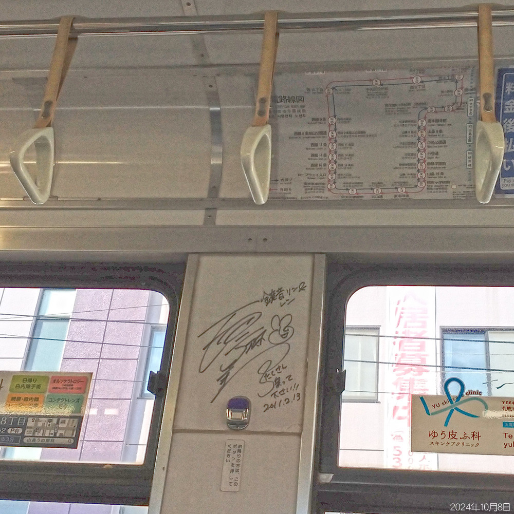 札幌市電の車内、降車ボタンの上の壁に2011年2月13日たくさん乗ってくださいと添え書きされた鏡音リン＆レンのマジック書きサインの写真