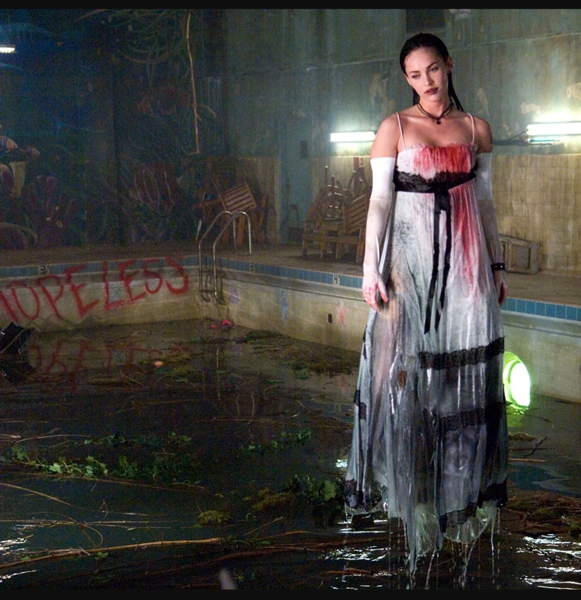 Jennifer in thr white prom dress drenched in water and blood standing in the swimming pool.