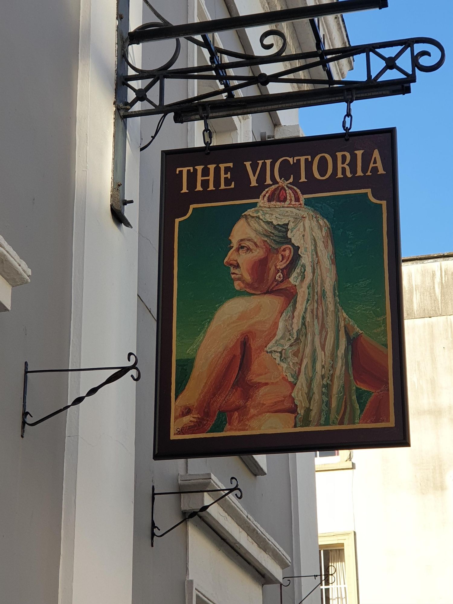 A photo of a pub sign in Bristol, England, with text 'THE VICTORIA' above a painting of Queen Victoria from behind. She's wearing a crown, but apparently nothing else.