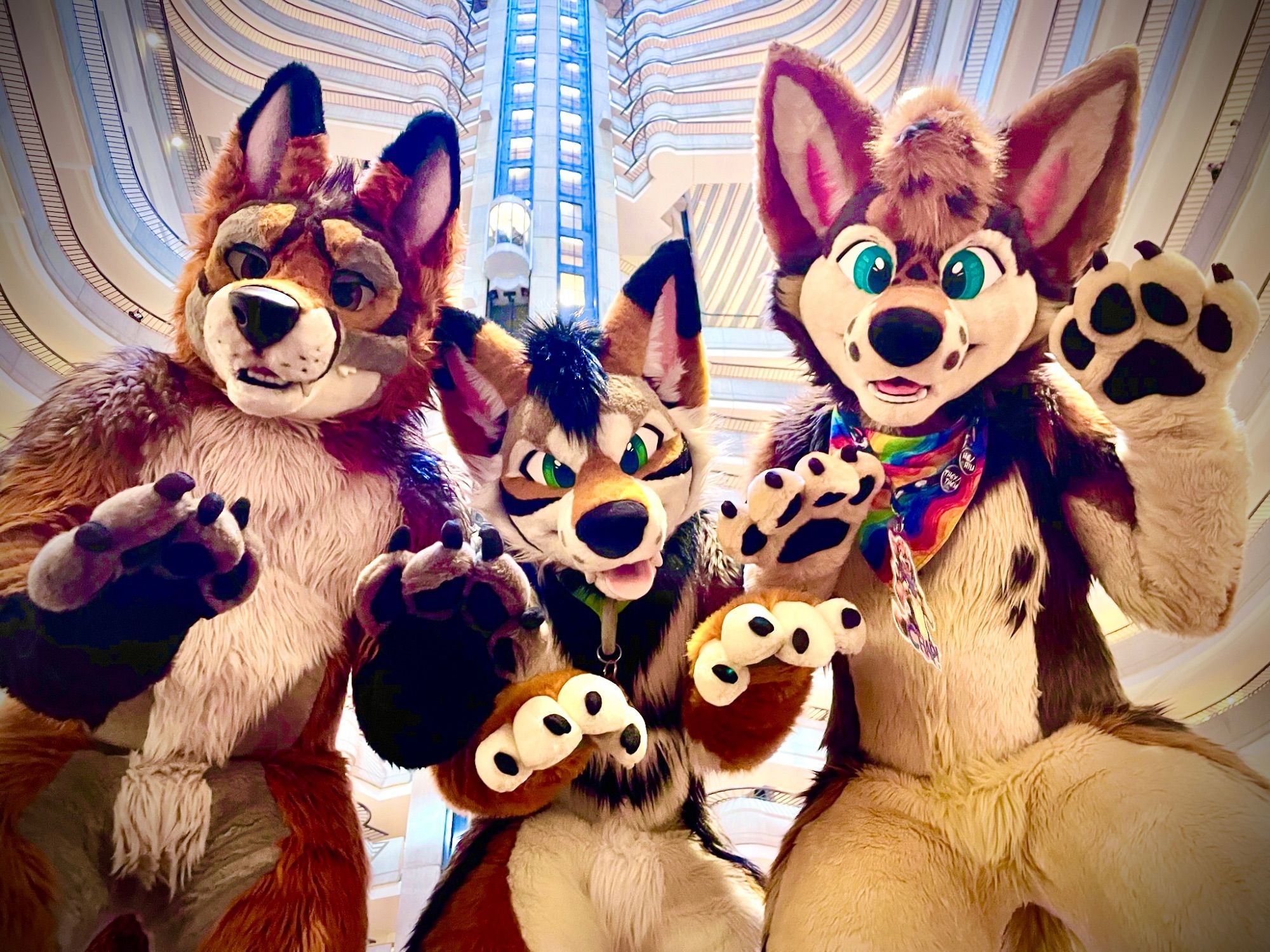 Three fursuiters (two coyotes and a maned wolf) pose for the camera