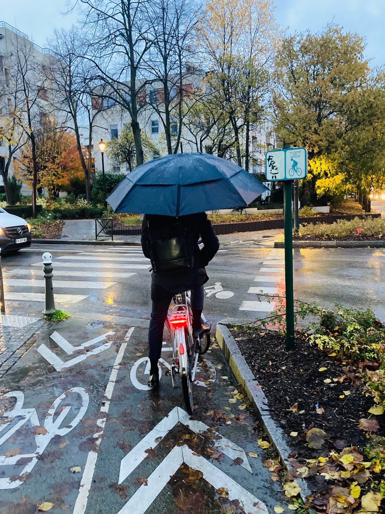 Homme à vélo sous la pluie avec un parapluie dans la main gauche