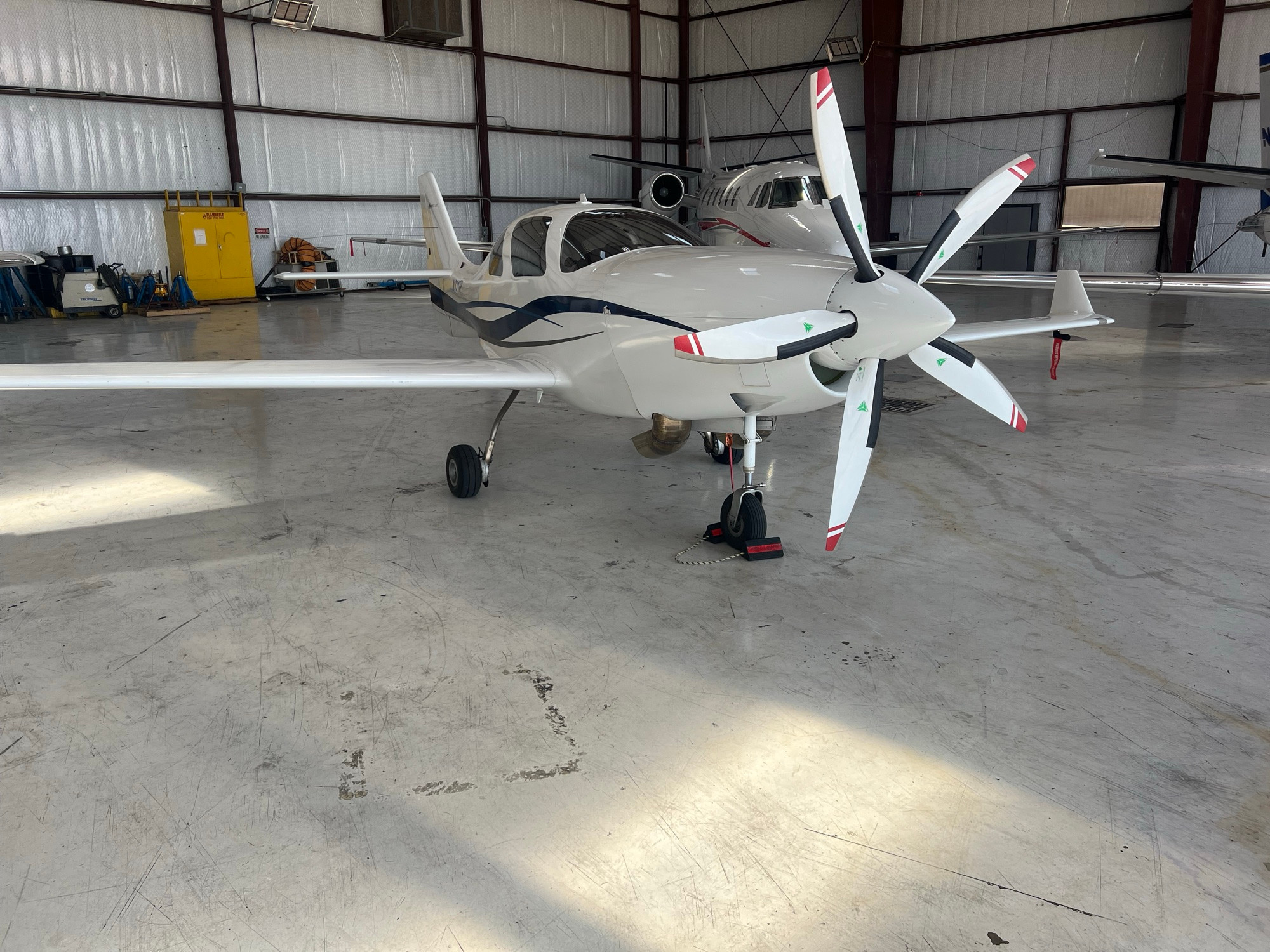 A white and blue Lancair 4 high performance airplane. One with the normal piston engine can already hit 300 knots. This has a more powerful turboprop with a much larger 5 blade propeller!
