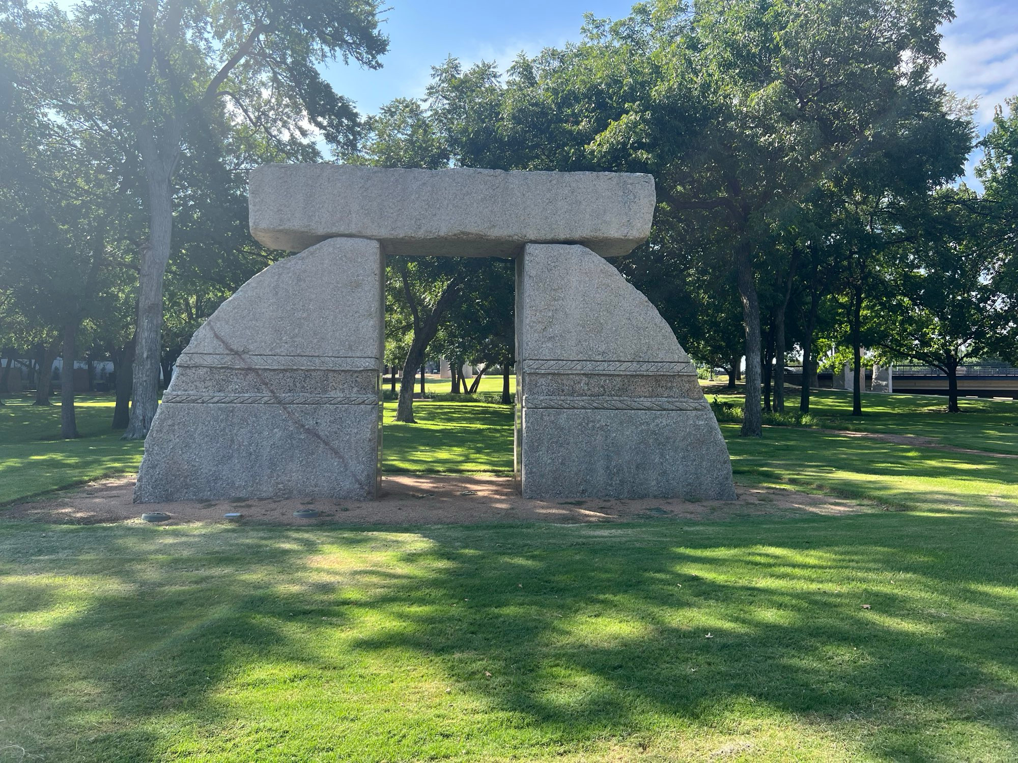 A stone arch gateway made up of two semicircular pillars and a crossover connecting them, opening towards a bundle of trees. The Gateway of Truth