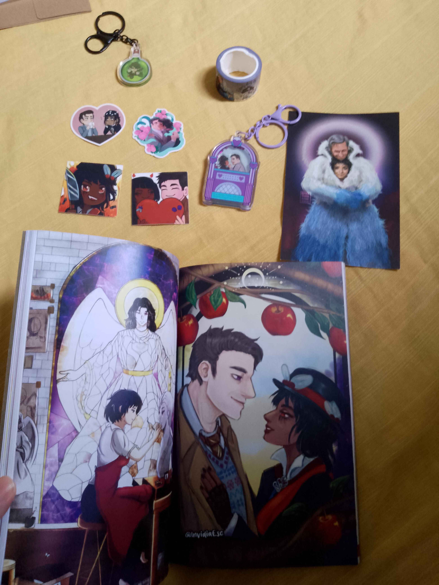 Red Tape Vol. 2 Zine (Magazine) and Merch from it. 
Gabriel and Beelzebub fanart, keychain, and stickers, washis.
Zine open with two images of drawings the one at right is mine.