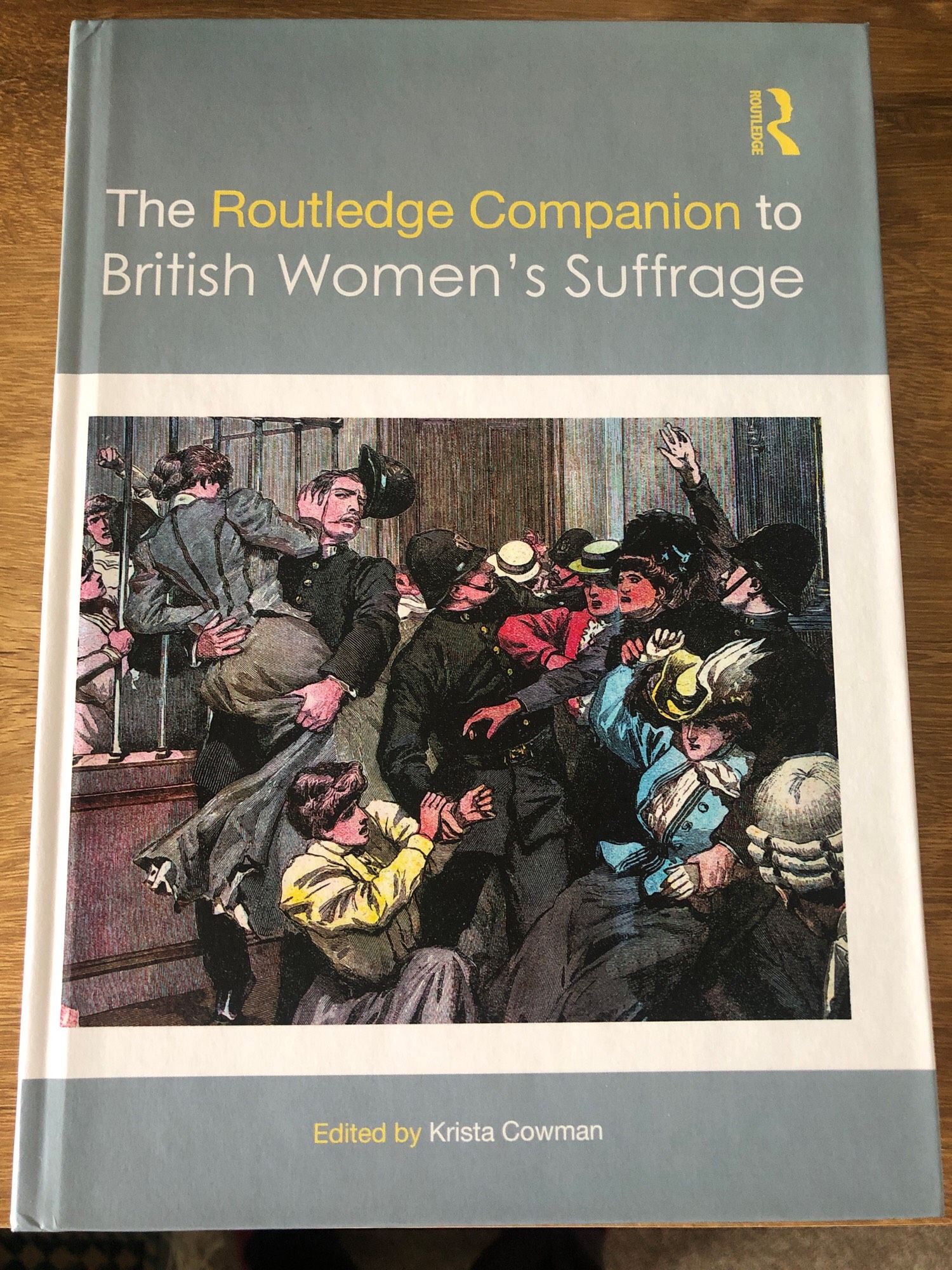 Front cover of a book ‘The Routledge Companion to British Women’s Suffrage’, edited by Krista Cowman, with a colour drawing of women wrestling with policemen