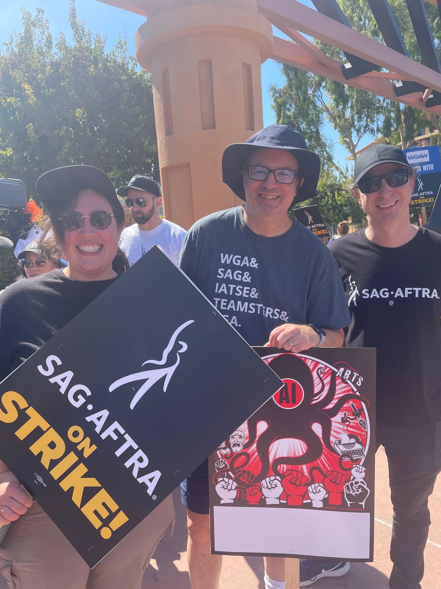 Three people with picket signs standing in front of the main Disney gate.