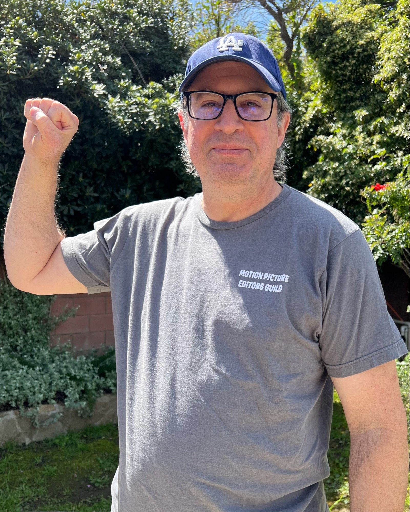 Me wearing my gray Motion Picture Editors Guild shirt, fist raised in solidarity.