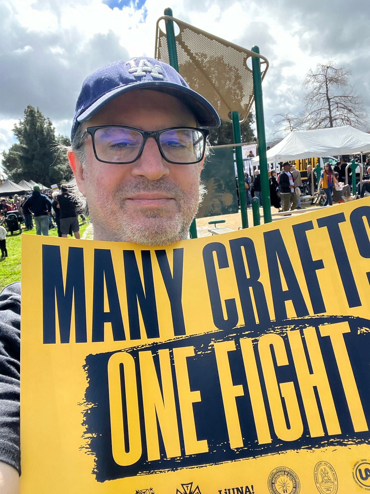 Me holding up a “Many Crafts, One Fight” union solidarity sign