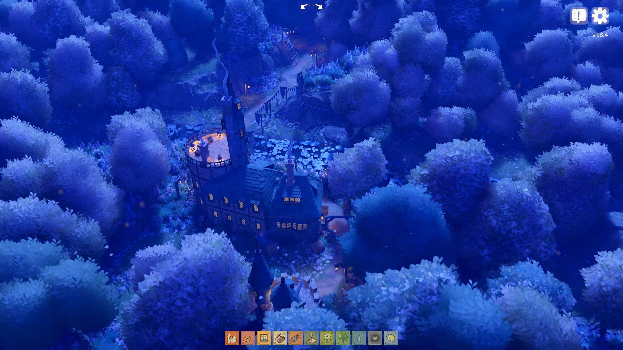 Screenshot from Tiny Glade game, from the builder mode. Aerial view of a backside of a strange building during night. Light is blinking from the windows of the round building. There are trees, and a small river on the other side of the building. Path is going towards the forest on the background.