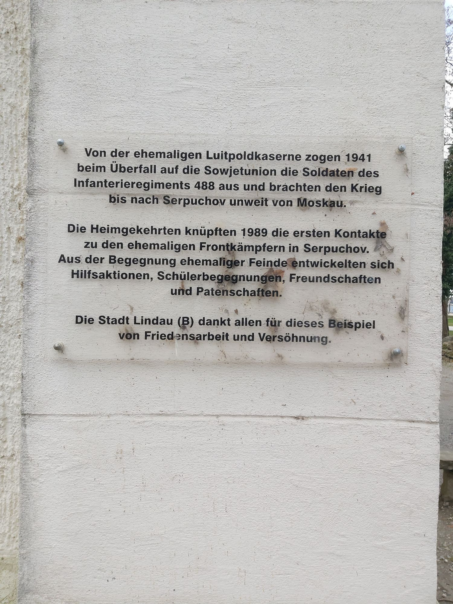 Eine Tafel, die an einem Haus angebracht ist. Darauf steht:
"Von der ehemaligen Luitpoldkaserne zogen 1941 beim Überfall auf die Sowjetunion die Soldaten des Infanterieregiments 488 aus und brachten den Krieg bis nach Serpuchov unweit von Moskau. 
Die Heimgekehrten knüpften 1989 die ersten Kontakte zu den ehemaligen Frontkämpfern in Serpuchov. Aus der Begegnung ehemaliger Feinde entwickelten sich Hilfsaktionen, Schülerbegegnungen, Freundschaften und Patenschaften. 
Die Stadt Lindau (B) dankt allen für dieses Beispiel von Friedensarbeit und Versöhnung."