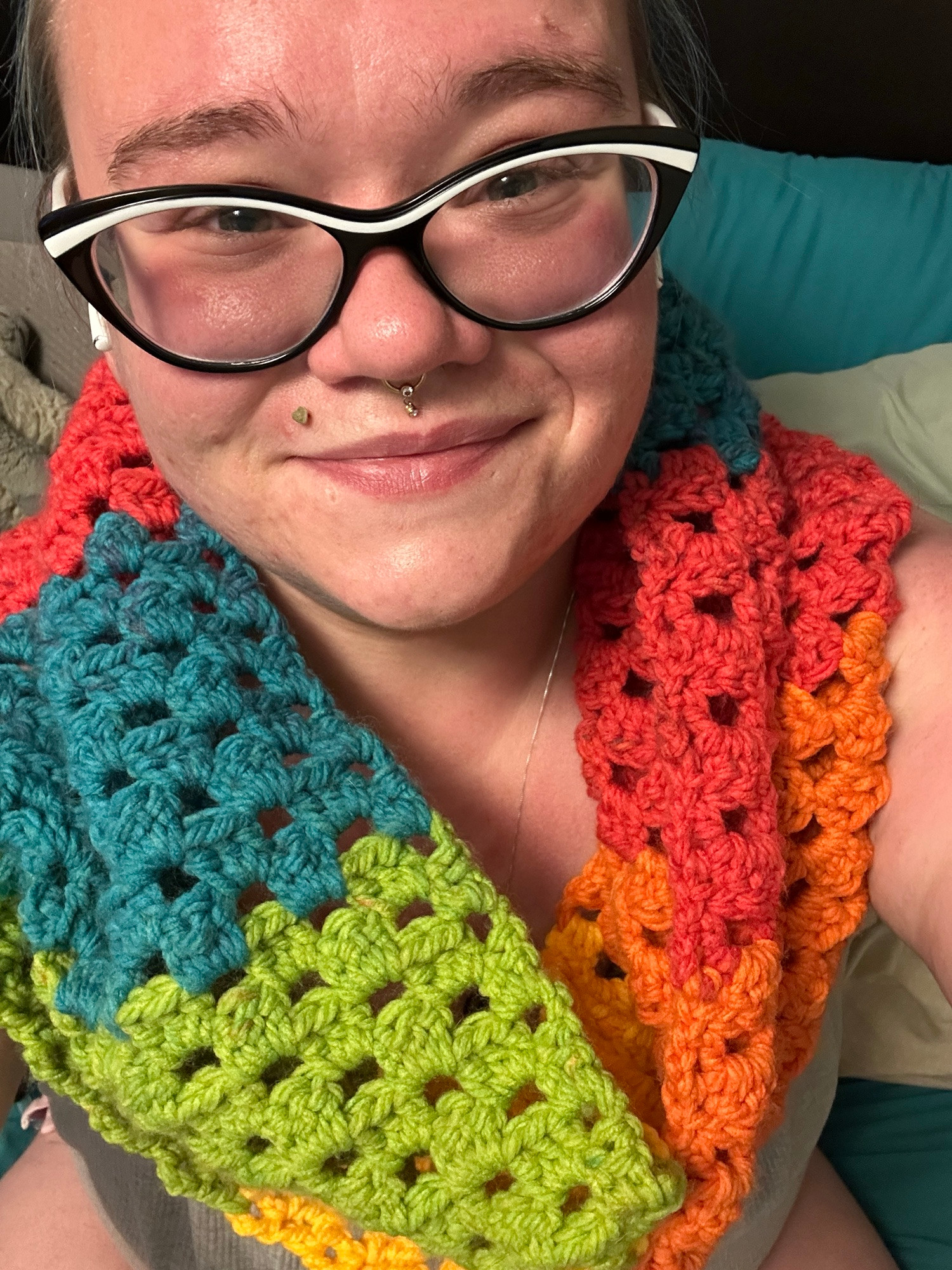 rem wearing a cute infinity scarf. it is rainbow colors and has an interesting texture. rem is smiling really big because it's happy