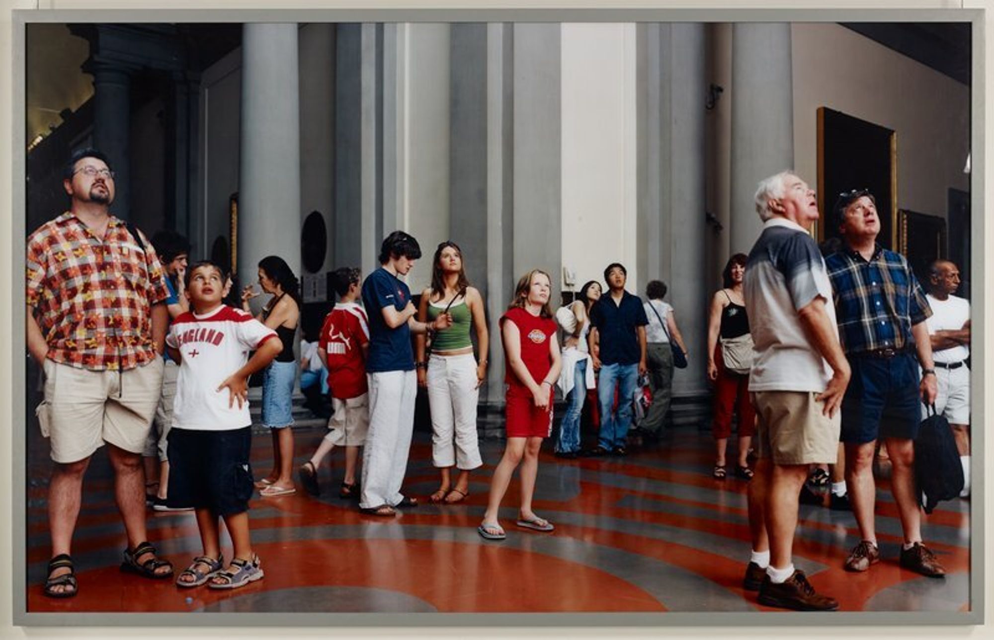 No. 9632; people looking up at object in museum; grey wood frame with Plexiglas
Thomas Struth was born in Geldern, Germany, near Düsseldorf, in 1954 and attended the Düsseldorf Academy from 1973-80, where he studied painting under the instruction of Gerhard Richter. For the last twenty years Thomas Struth has been photographing in the galleries of European and American museums, capturing viewers in the act of looking, often at recognizable works of art. More recently he has created images in which the art object is not visible and goes unidentified, as in the case of this image. A little museum sleuthing reveals that the audience here is taking in Michelangelo’s David, one of the world’s best-known sculptures. In every picture from his ongoing series “Museum Photographs,” Struth makes the viewers his—and consequently our—subject. In Audience, we look at how museum-goers, like us, respond to and perceive art in museums.