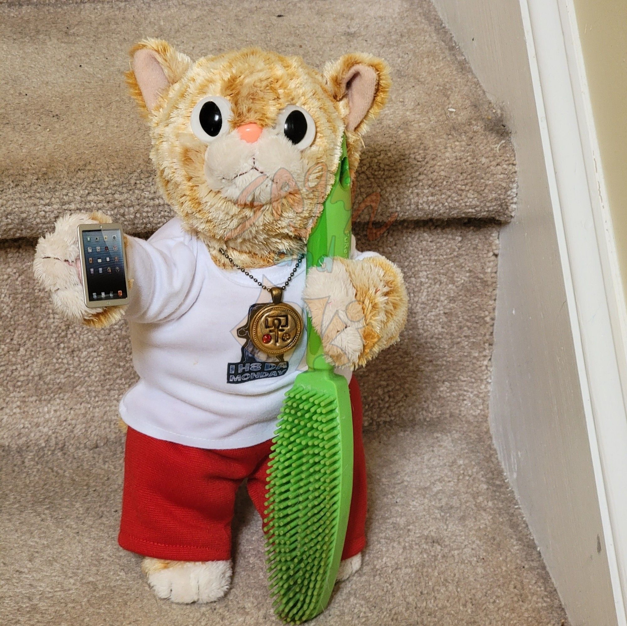 An orange plush cat in sweatpants and a tee stands on the stairs and holds a tiny tablet and a silicone brush used to scrape pet hair off carpet.