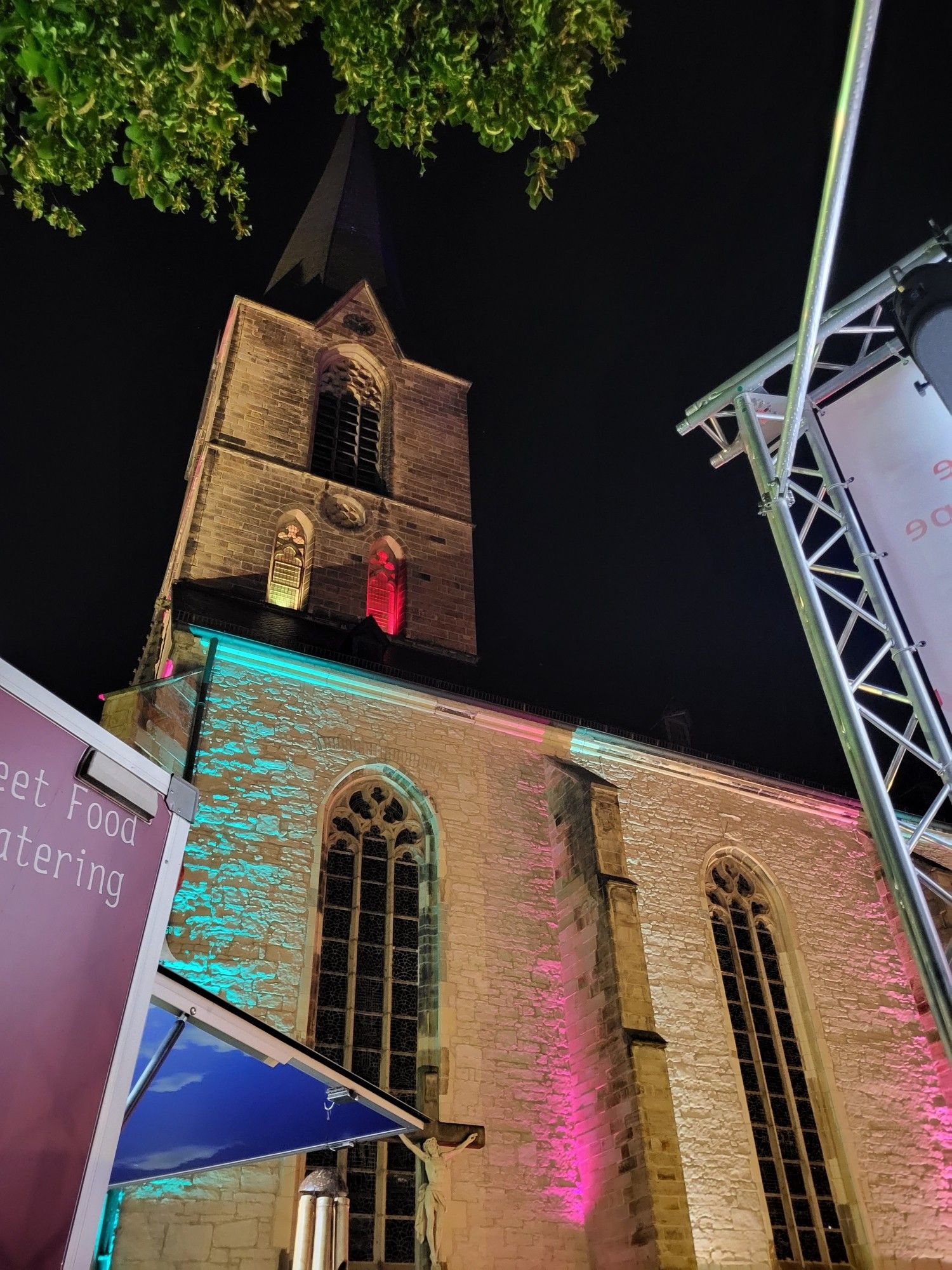 Aus der Froschperspektive ist eine alte Kirche ein erhabenenes Bauwerk.  Diese wurde in gelb, rot, grün und pink angestrahlt.